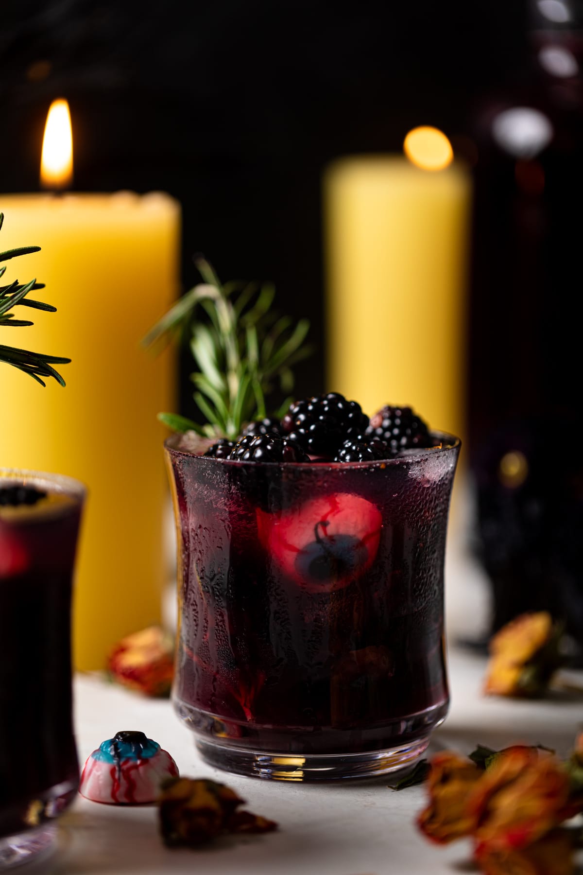 Dark Blueberry Blackberry Mocktail in a small glass in front of lit candles