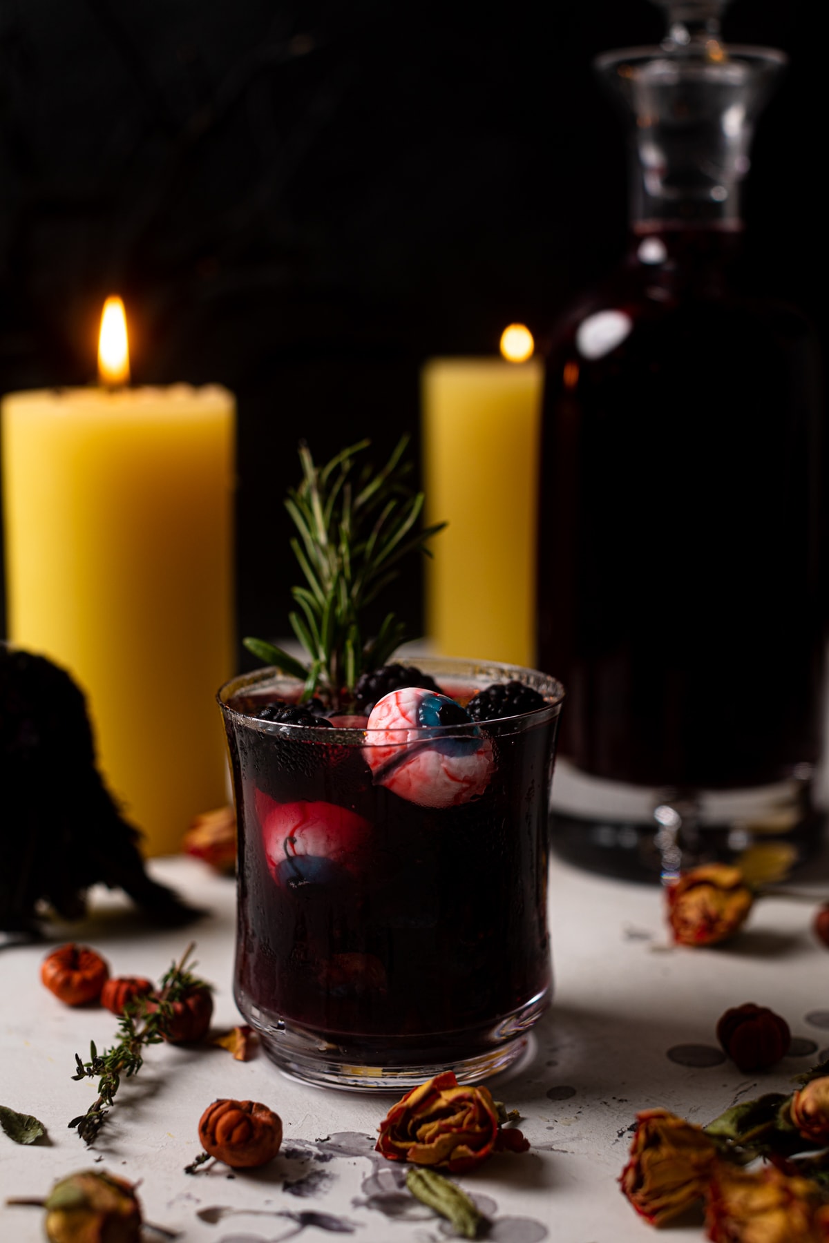 Dark Blueberry Blackberry Mocktail in a small glass in front of lit candles