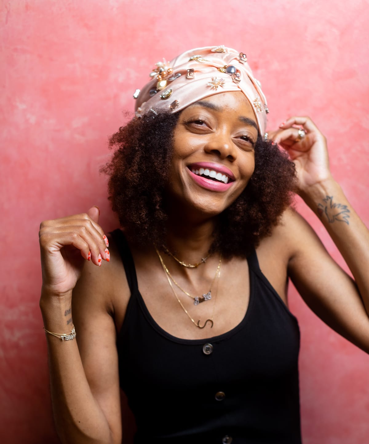 Shanika smiling in a black tank and a jeweled head wrap
