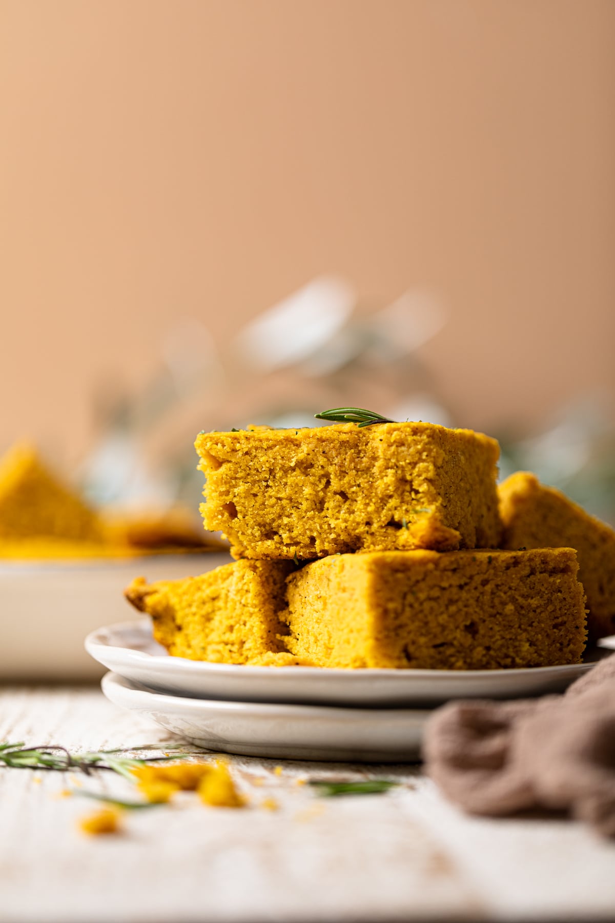 Pieces of Brown Butter Pumpkin Cornbread piled onto two small, stacked plates