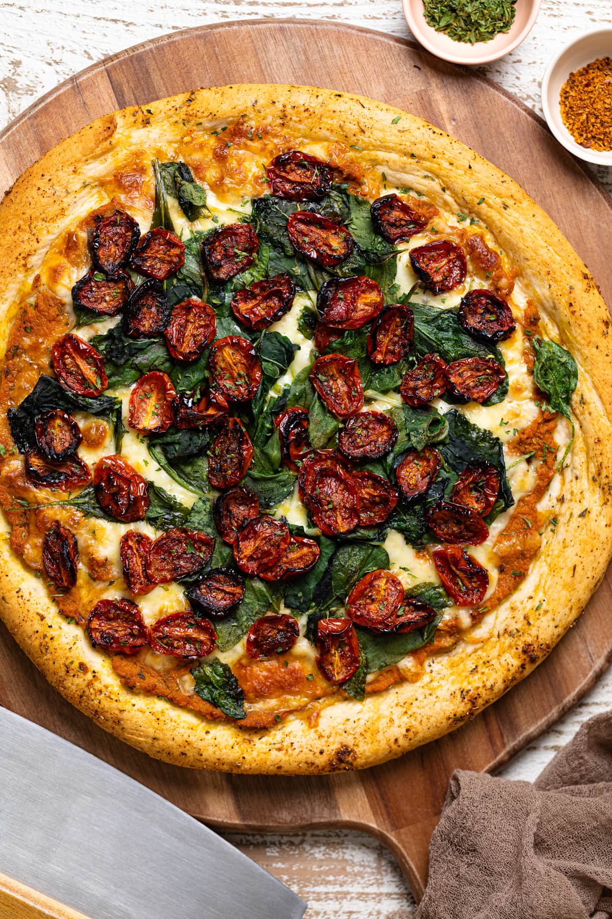 Unsliced Cajun Roasted Veggie Pumpkin Pizza on a wooden board