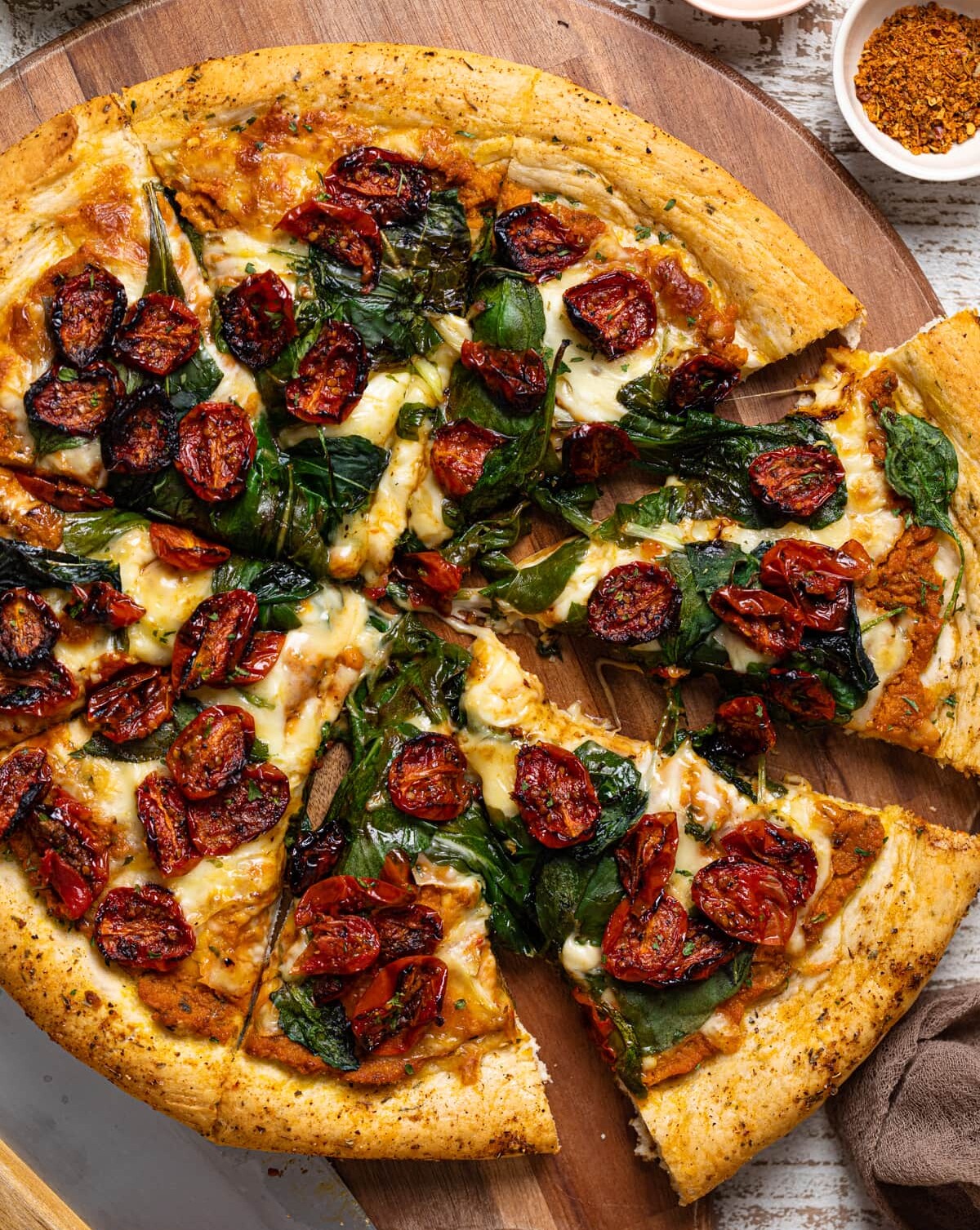 Sliced Cajun Roasted Veggie Pumpkin Pizza on a wooden board