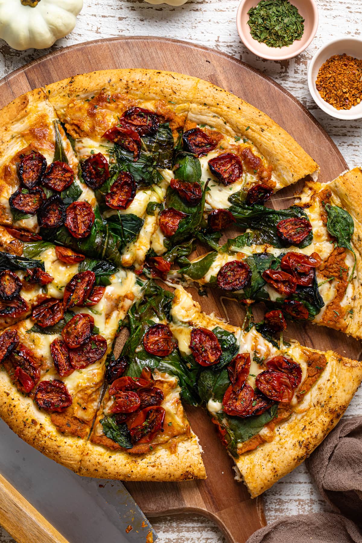 Sliced Cajun Roasted Veggie Pumpkin Pizza on a wooden board