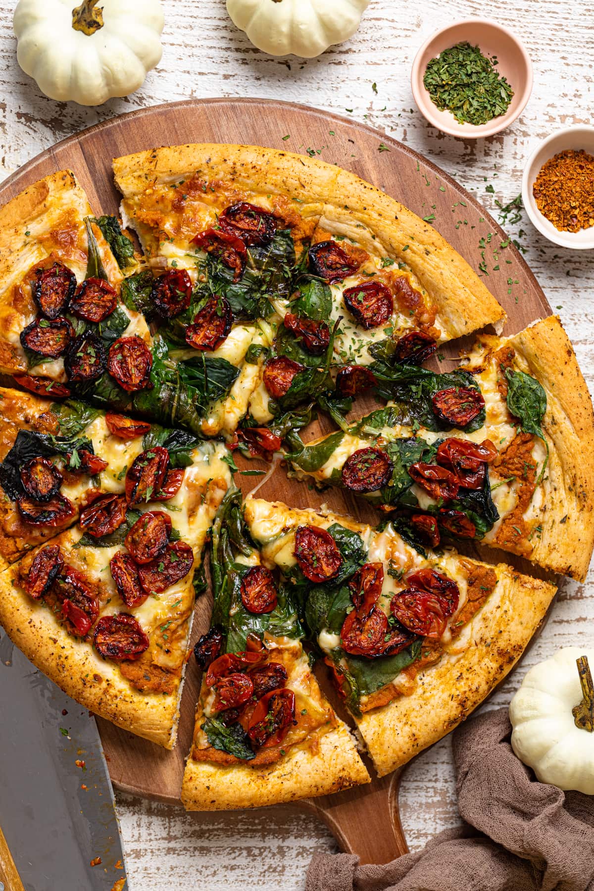 Sliced Cajun Roasted Veggie Pumpkin Pizza on a wooden board