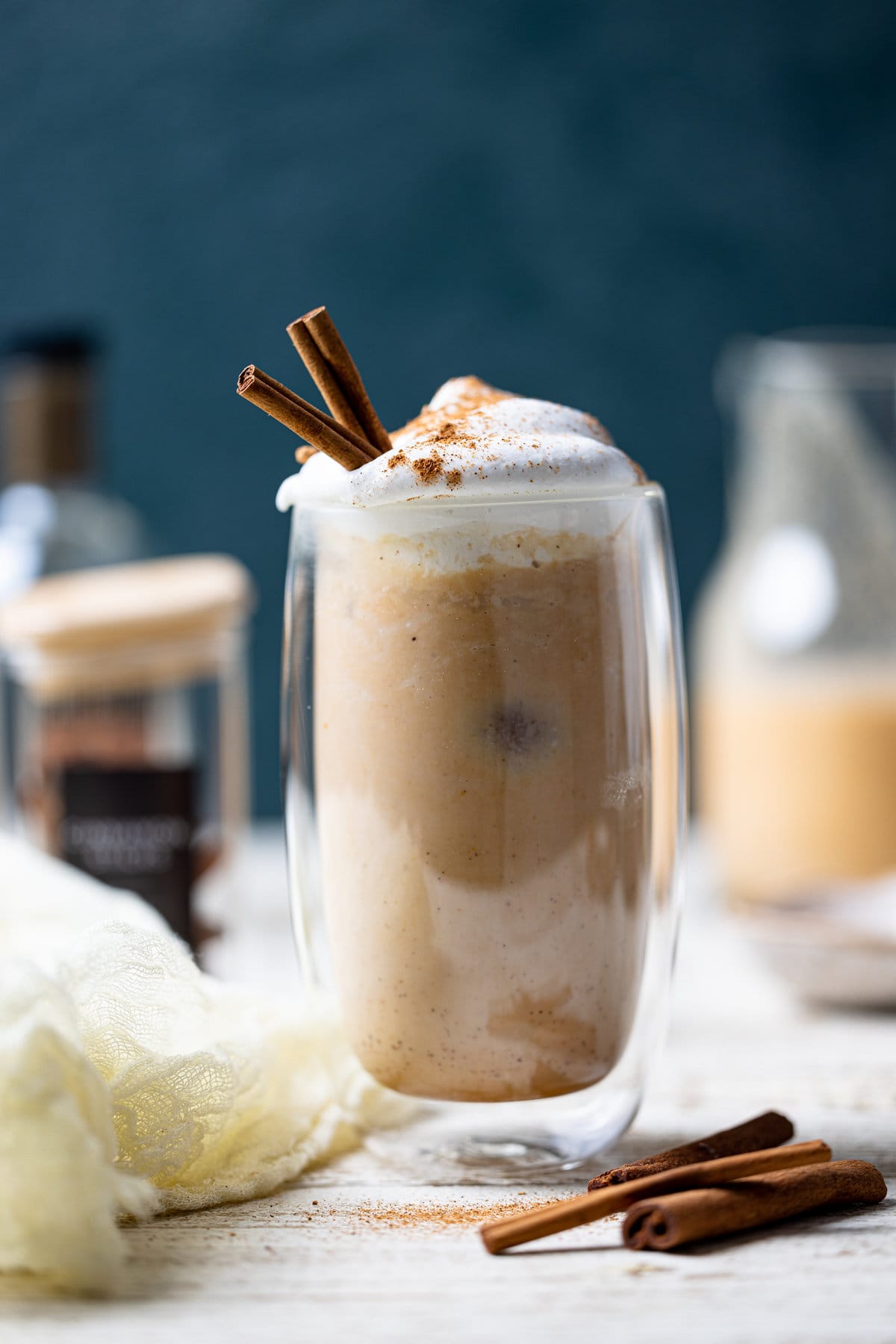 Glass of Dairy-Free Iced Pumpkin Spice Latte with two cinnamon sticks