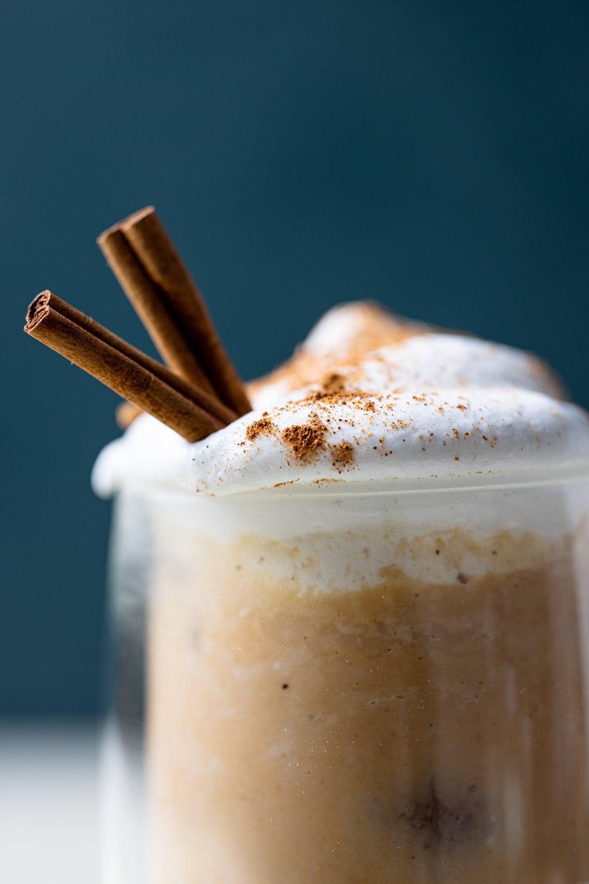 Closeup of a glass of Dairy-Free Iced Pumpkin Spice Latte with two cinnamon sticks