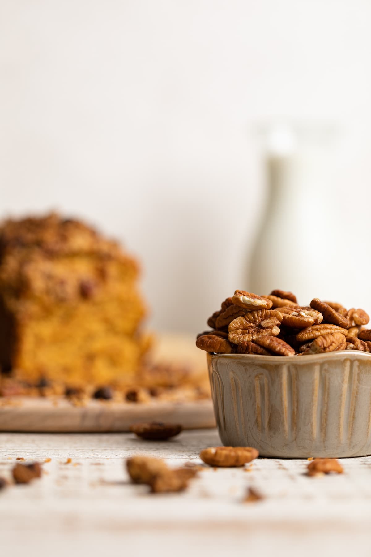 Bowl of pecans in front of a loaf of Vegan Sweet Potato Crumble Bread