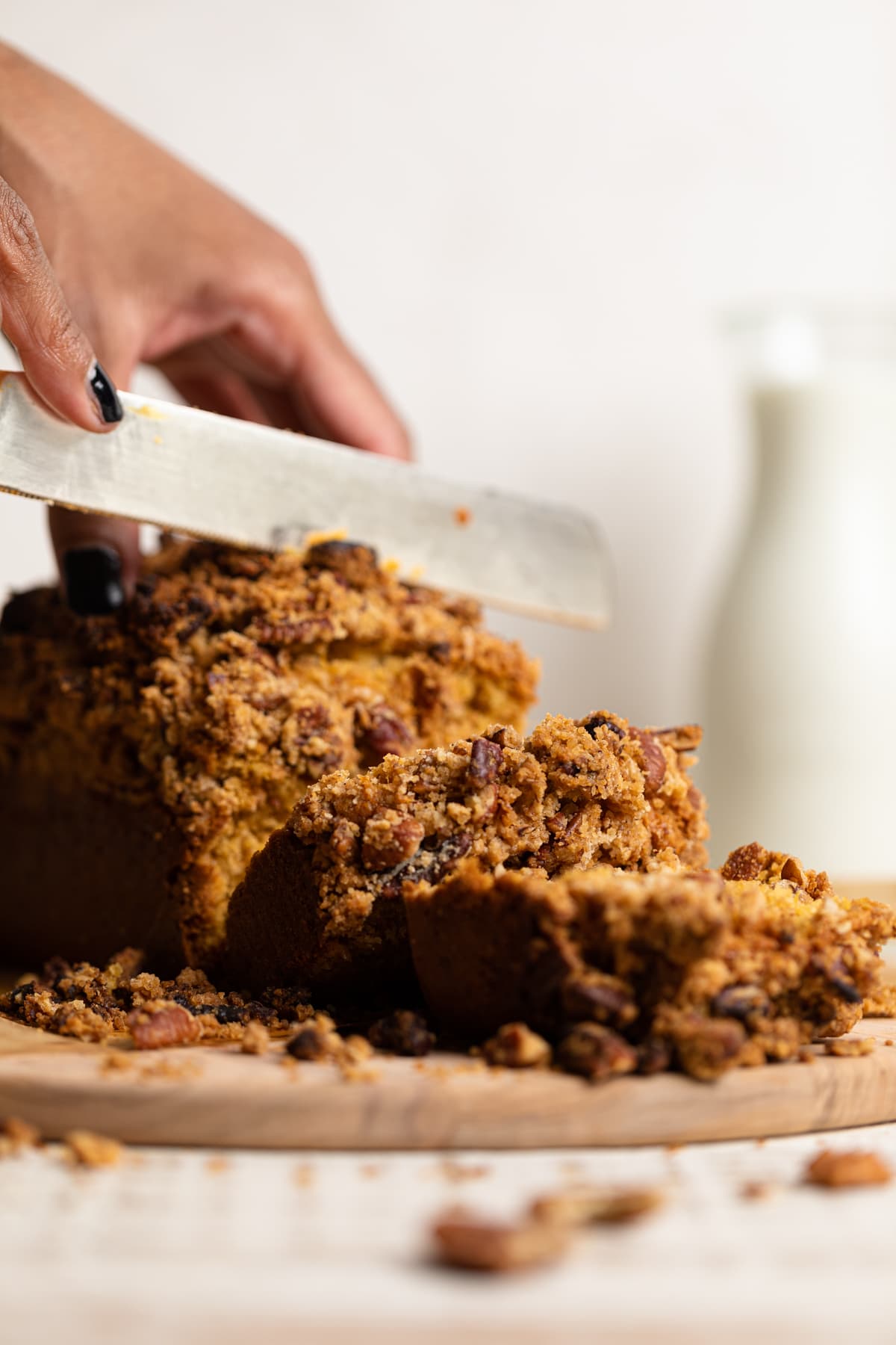 Hands using a knife to slice Vegan Sweet Potato Crumble Bread