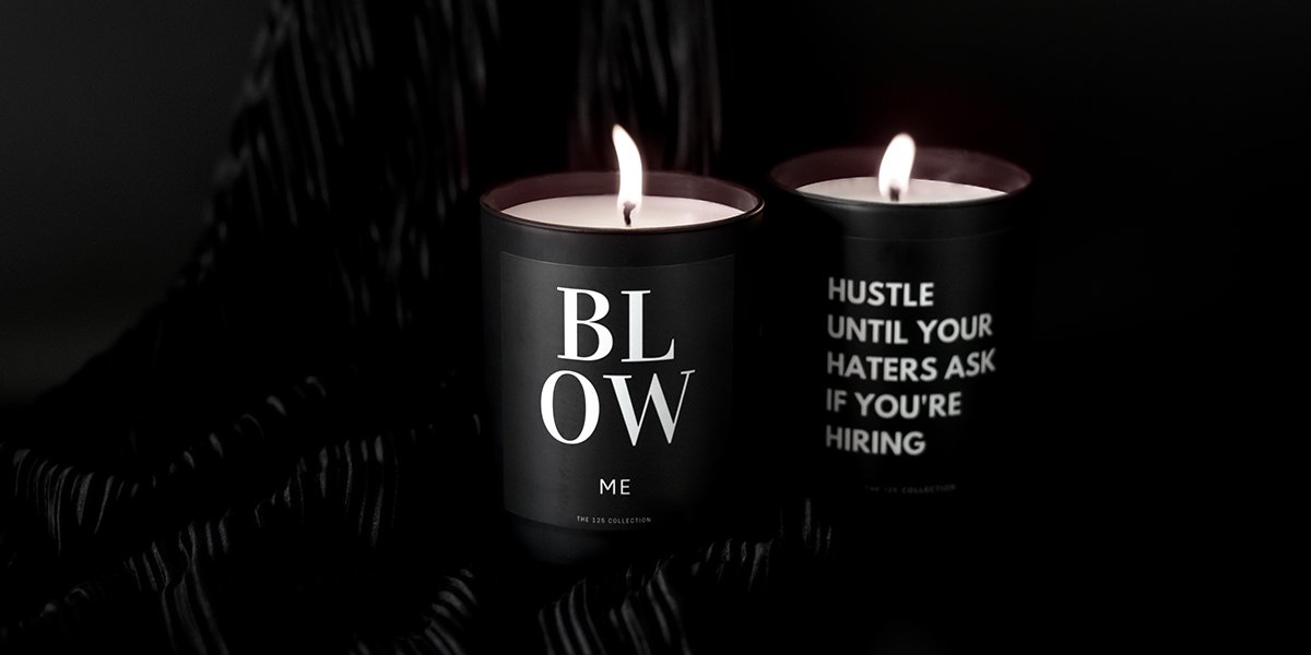 White candles in black candle holders that read: \"BL OW me\" and \"Hustle until your haters ask if you\'re hiring\" 