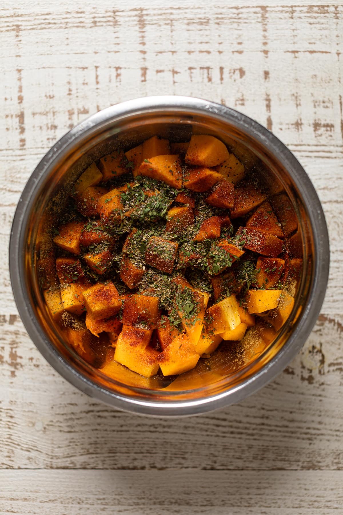 Chopped butternut squash and seasonings in a bowl