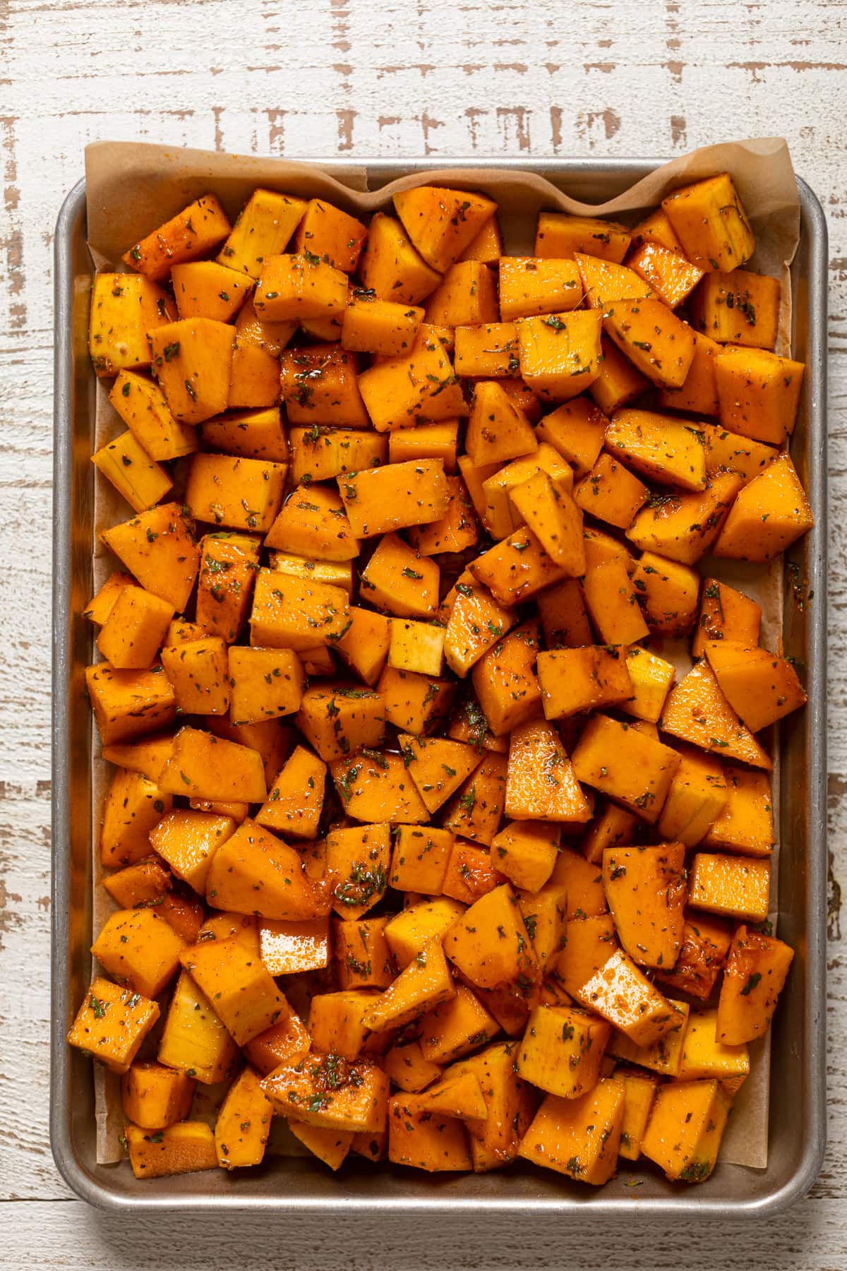 Seasoned butternut squash pieces on a baking sheet