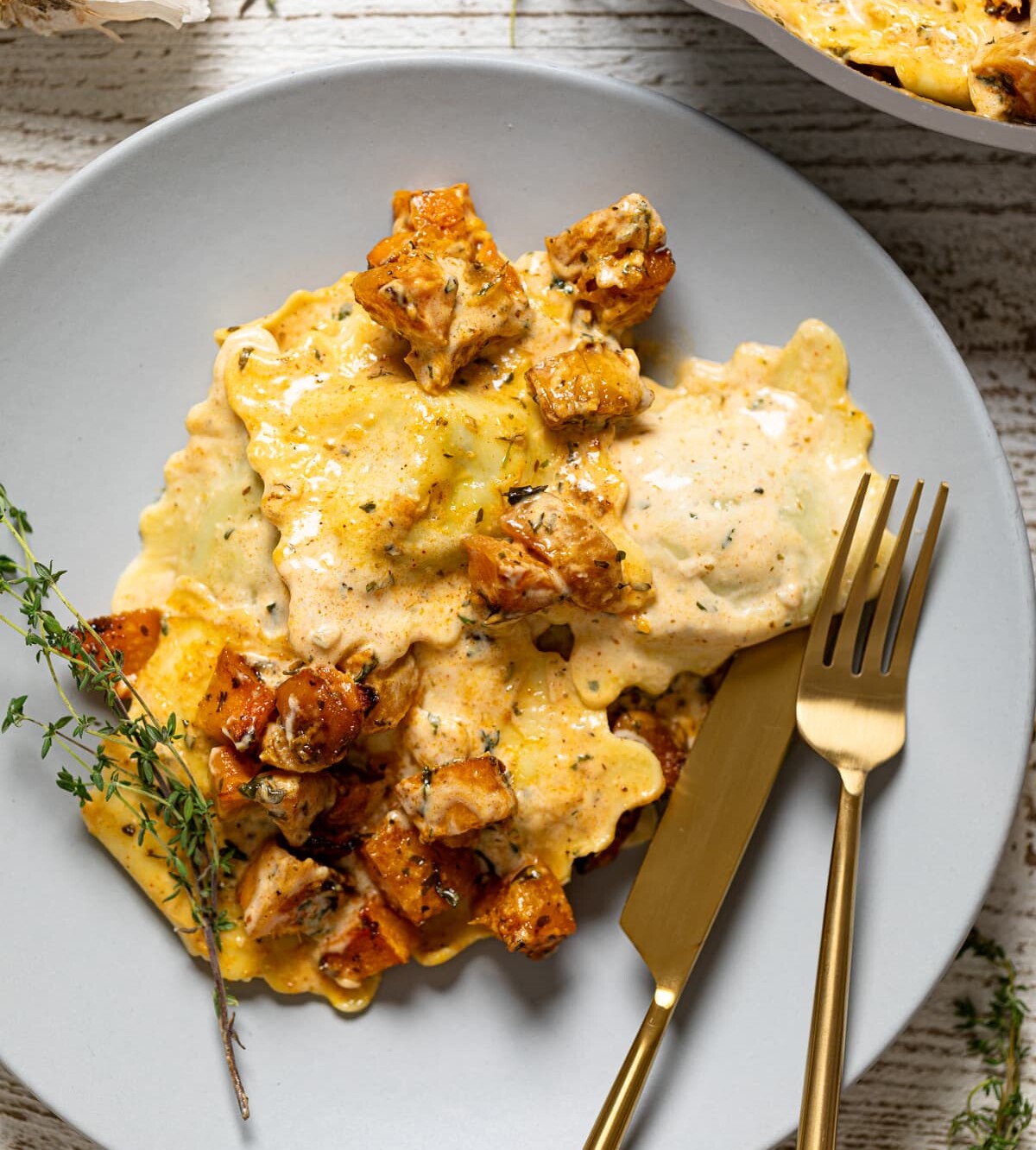 Fork and knife on a grey plate with Roasted Butternut Squash Pasta with Parmesan Garlic Sauce