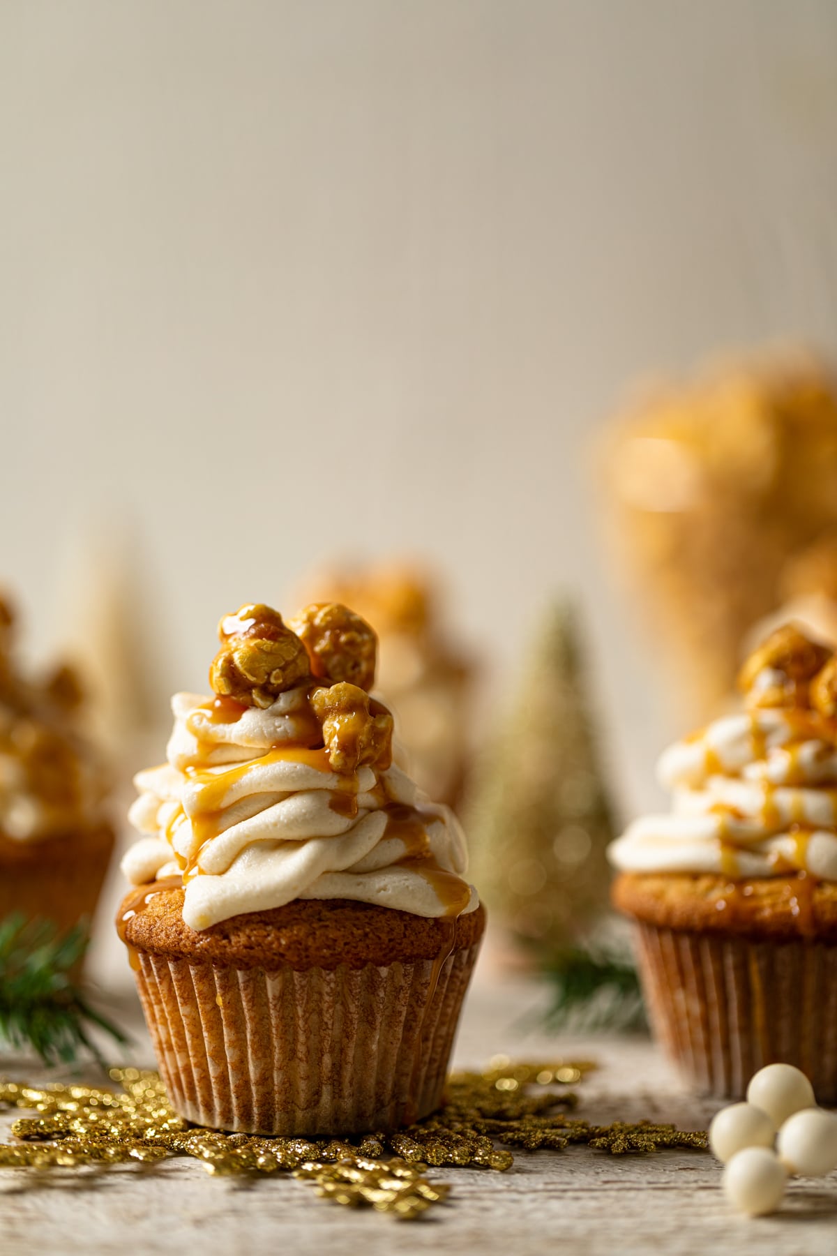 Caramel Eggnog Cupcake topped with caramel popcorn and caramel drizzle and on a golden snowflake decoration