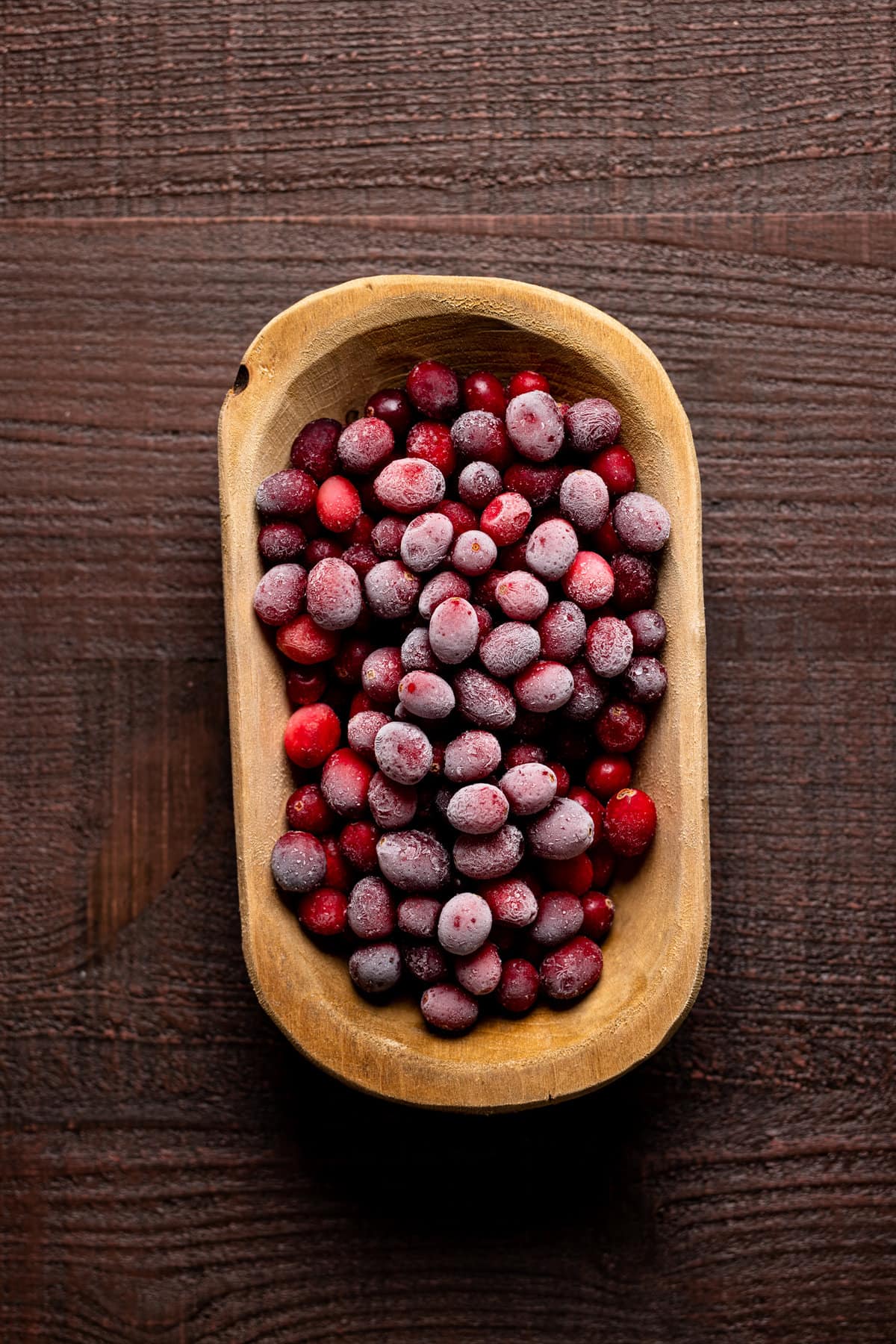 Wooden bowl of frozen cranberries