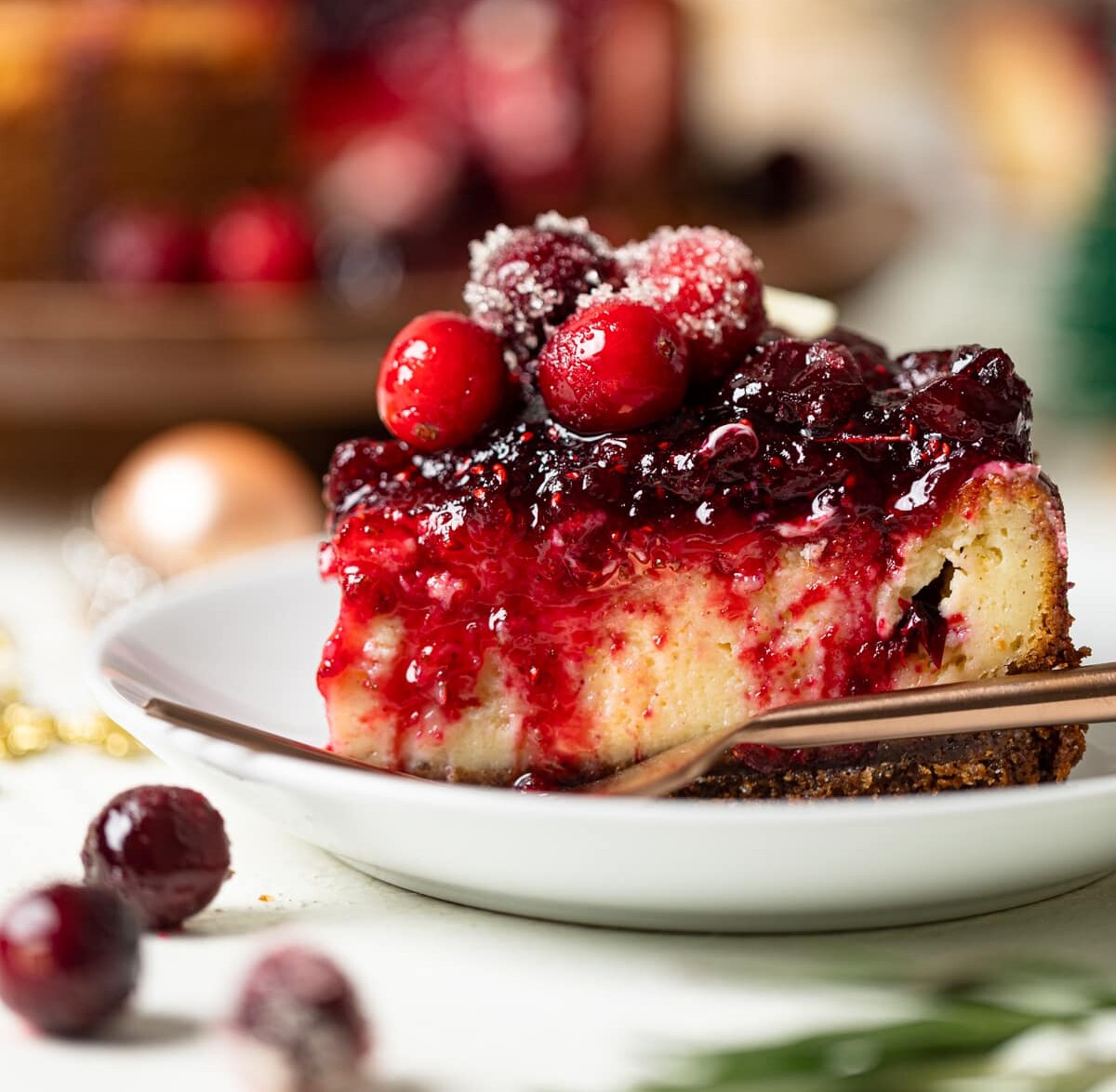 Slice of White Chocolate Cheesecake with Cranberries on a small plate with a fork