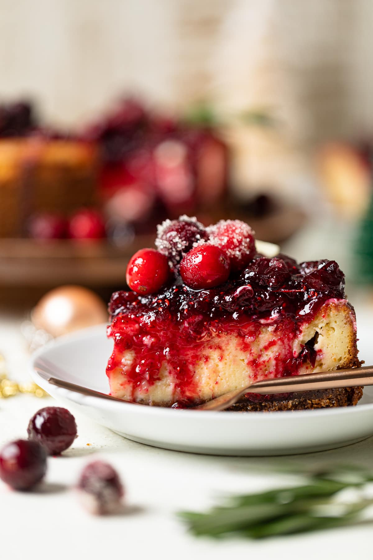 Slice of White Chocolate Cheesecake with Cranberries on a small plate with a fork