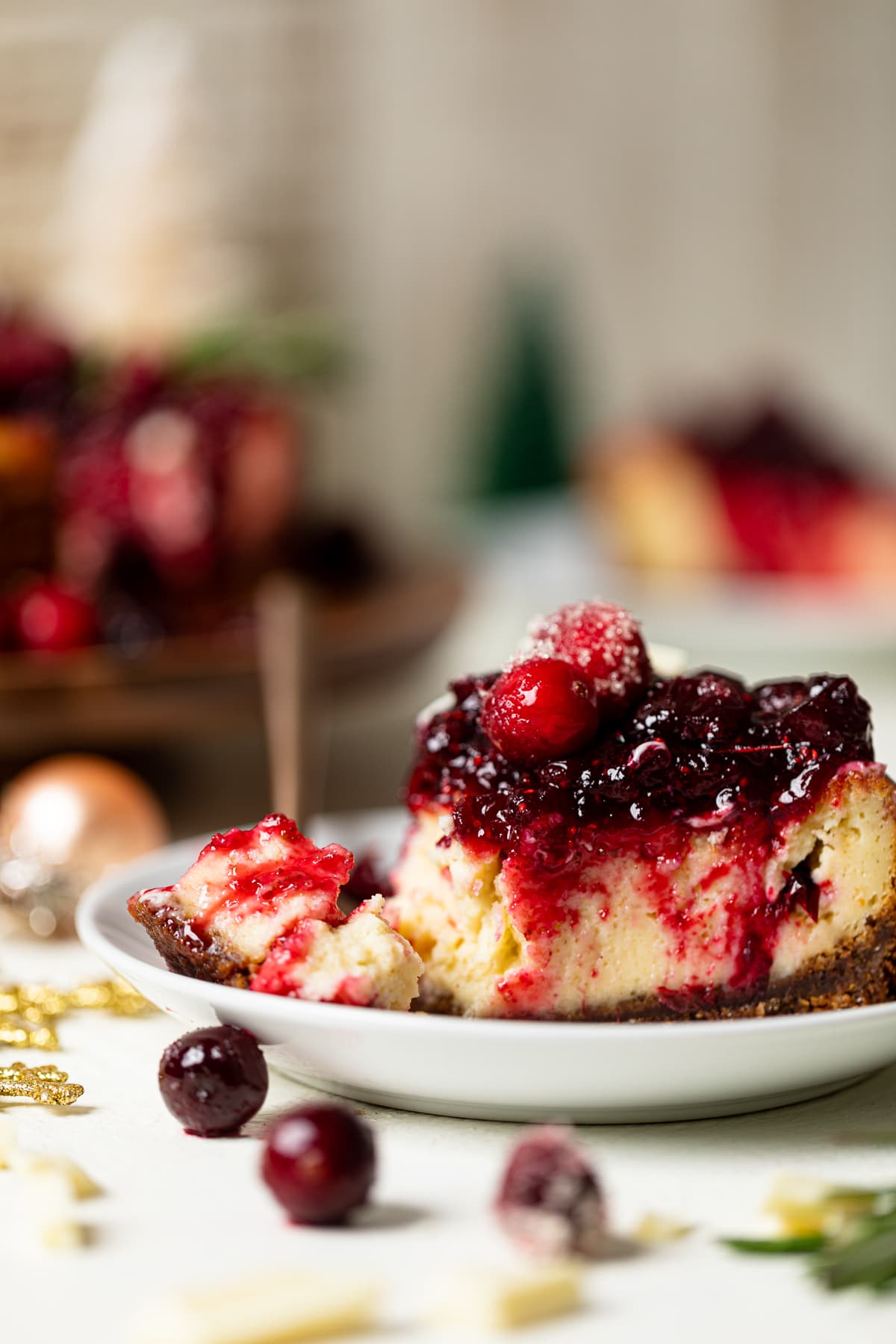Slice of White Chocolate Cheesecake with Cranberries on a plate with a fork that has a small piece of cheesecake