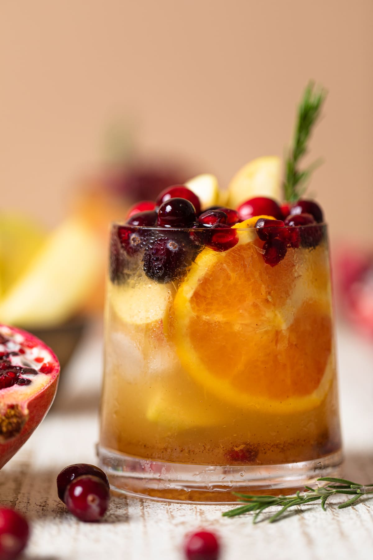 Closeup of a Thanksgiving Punch Mocktail topped with pomegranate arils, cranberries, and a rosemary sprig