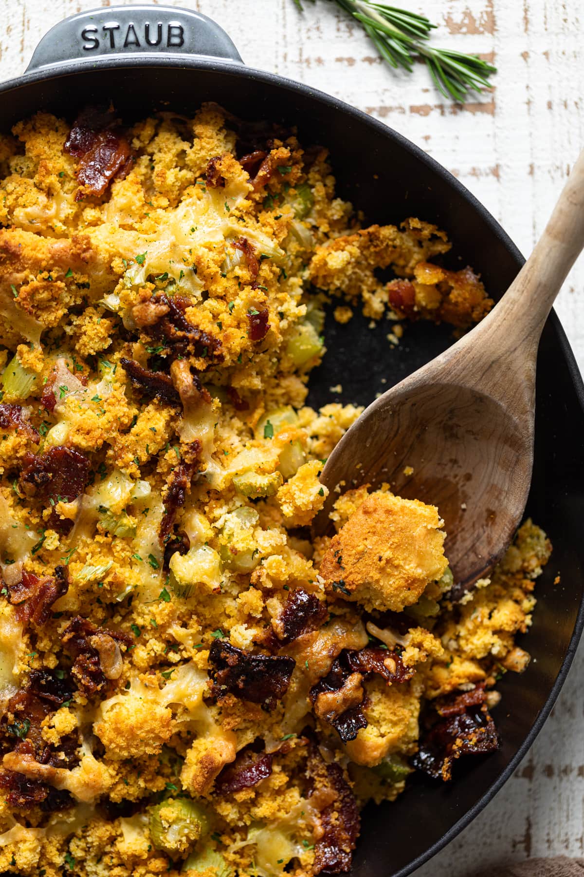Wooden spoon scooping some Southern-Styled Cornbread Stuffing out of a skillet