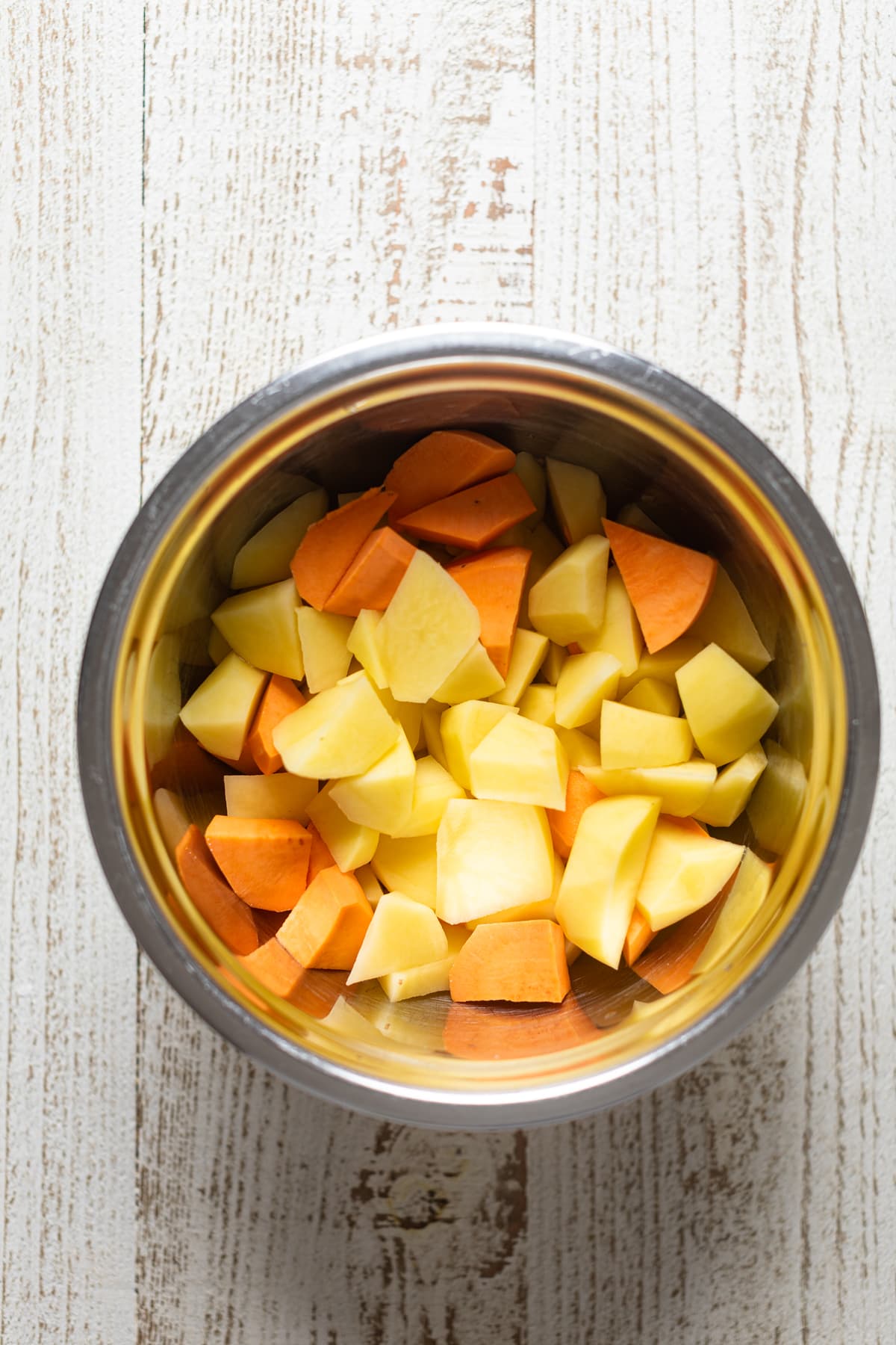 Bowl of chopped and peeled potatoes and sweet potatoes