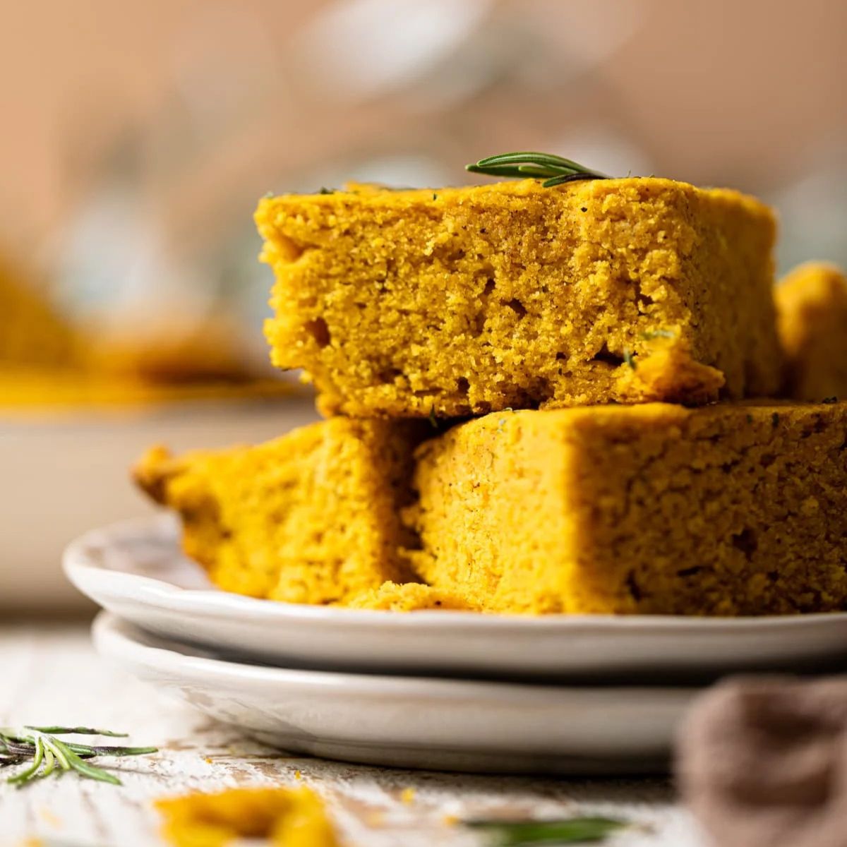 Stack of sliced Maple Brown Butter Pumpkin Cornbread on two plates.