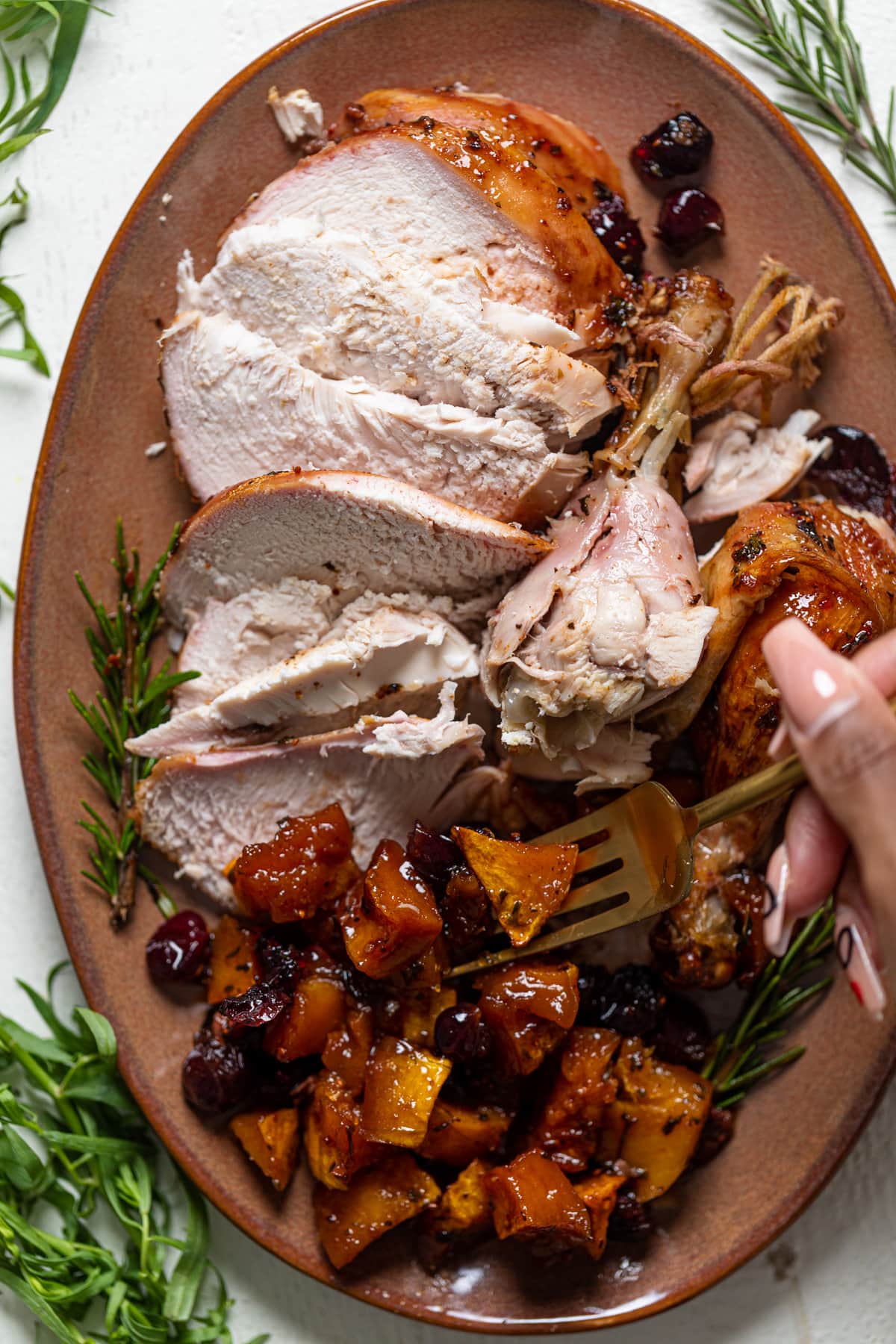 Fork grabbing roasted butternut squash from a platter of Cranberry Maple Roast Chicken