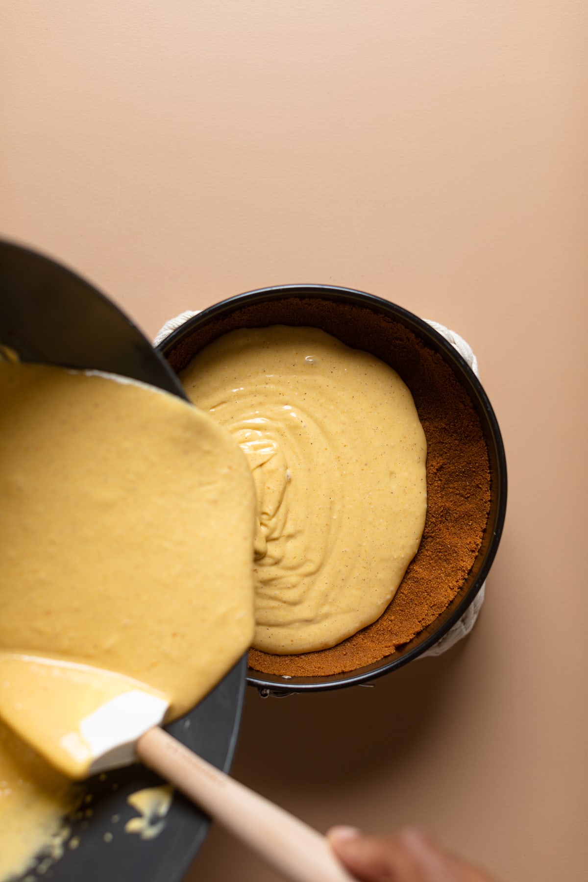 Pumpkin Cheesecake filling pouring onto Biscoff crust