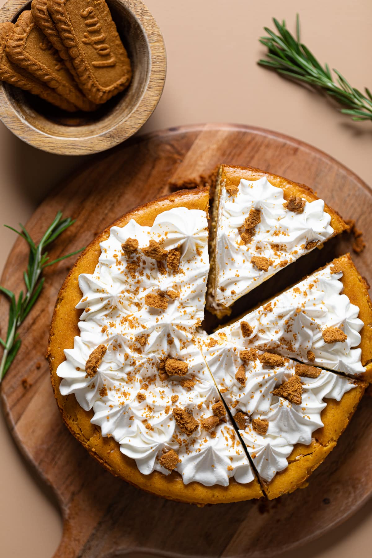 Partially-sliced Pumpkin Cheesecake with Biscoff Cookies on a wooden board