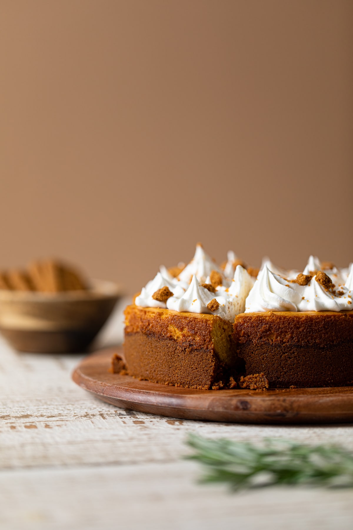 Side view of Pumpkin Cheesecake with Biscoff Cookies on a wooden board/ the best holiday dessert