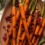 Closeup of Maple Herb Glazed Carrots and Cranberries on a light brown serving platter