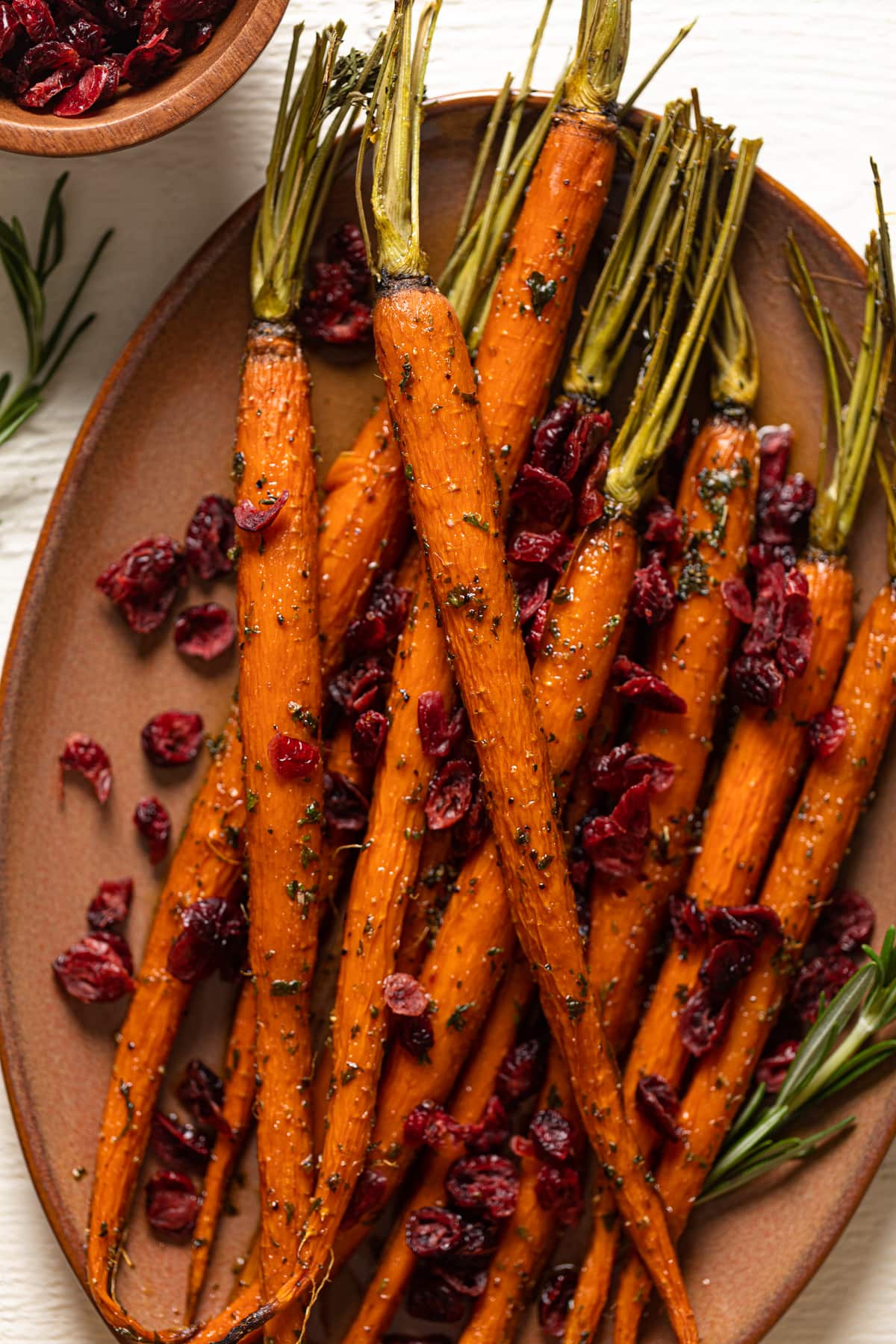 Closeup of Maple Roasted Carrots and Cranberries on a light brown serving platter