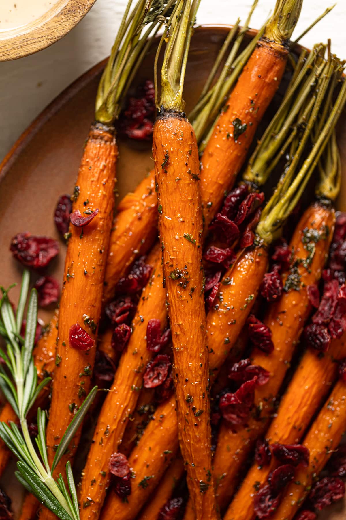 Closeup of Roasted Carrots and Cranberries on a light brown serving platter