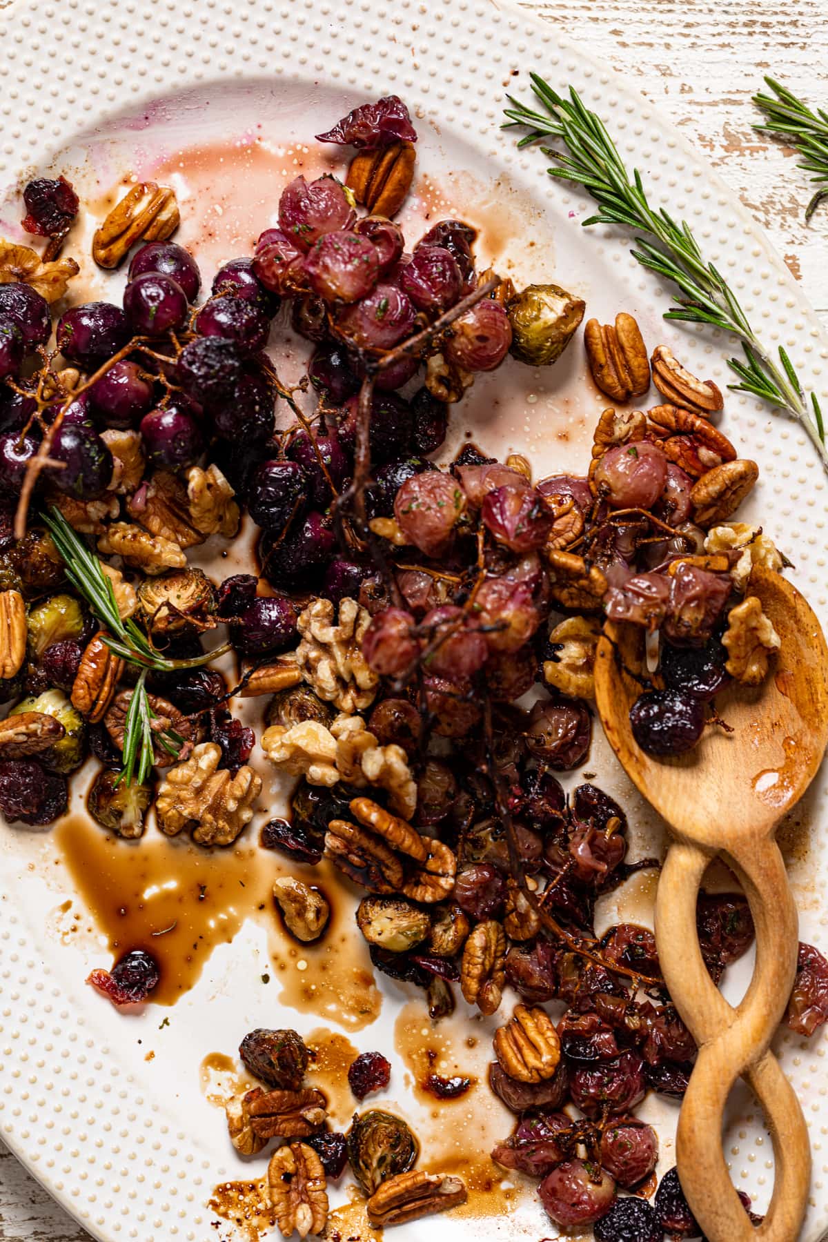 Wooden spoon on a half-served platter of Roasted Grapes and Brussels Sprouts