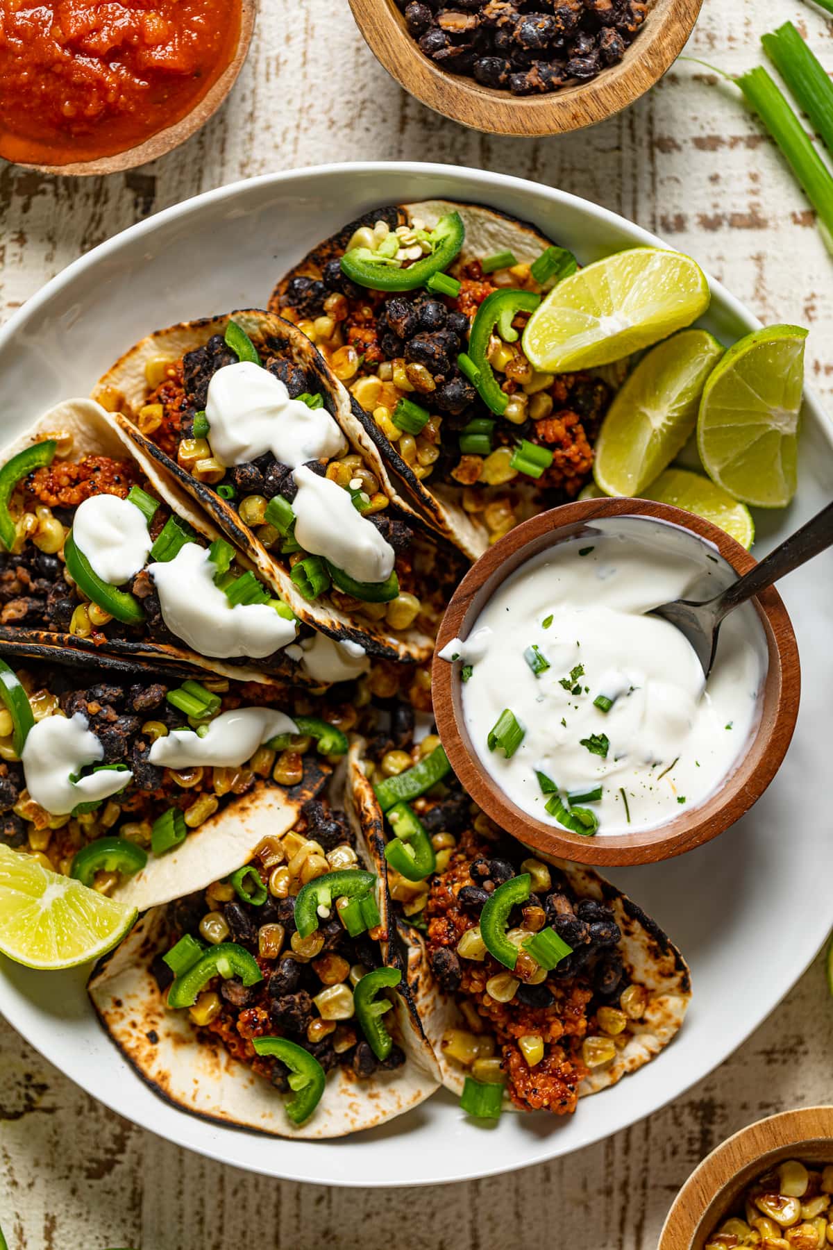 Plate of Spicy Sofritas Quinoa Tacos with lime sour cream and lime wedges