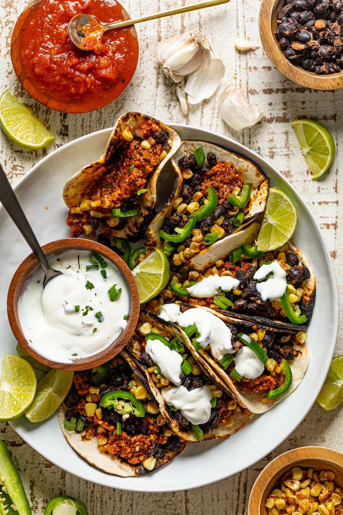 Overhead shot of a plate of Spicy Sofritas Quinoa Tacos with lime sour cream and lime wedges