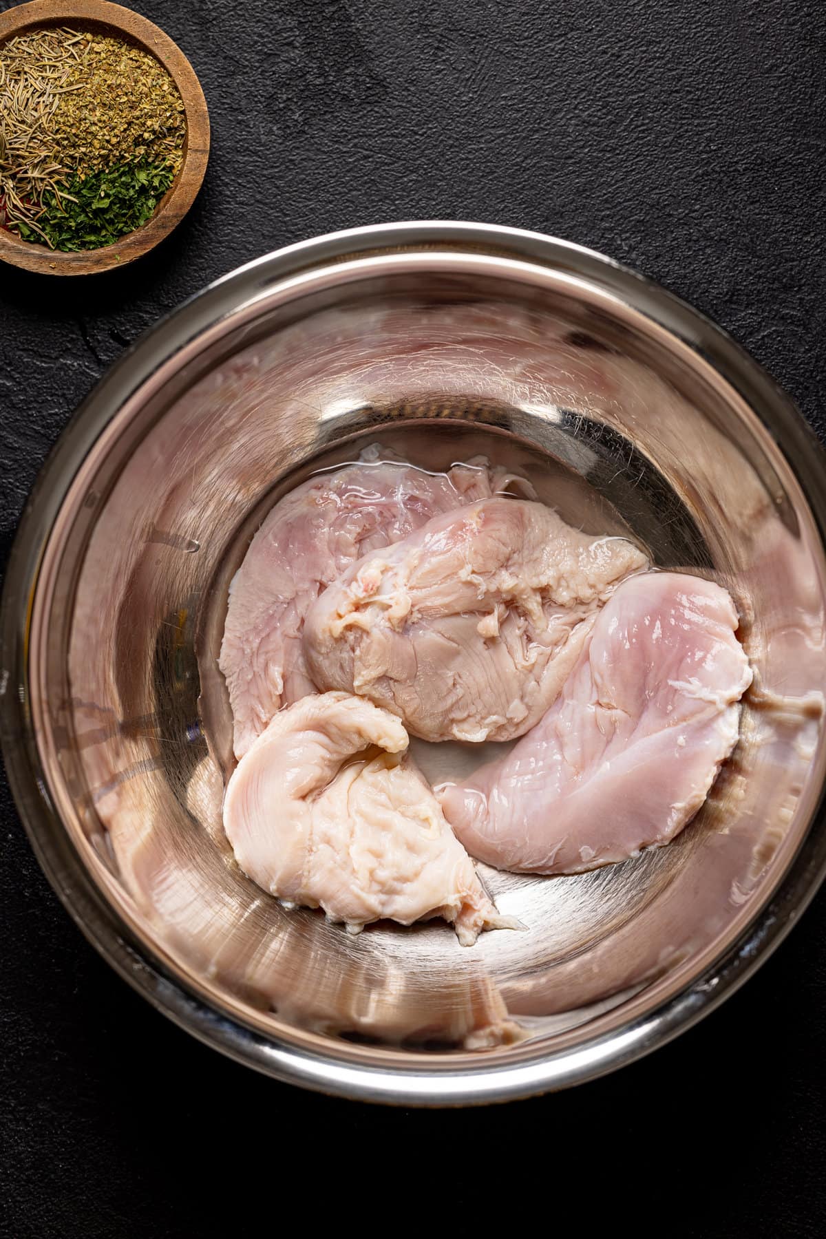Raw chicken in a metal bowl
