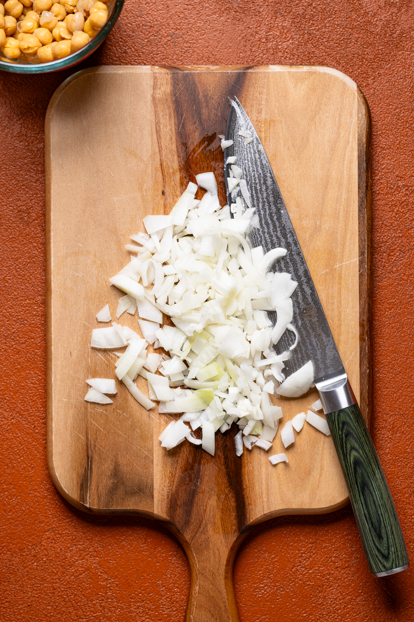 Chopped onion on a cutting board with a knife.