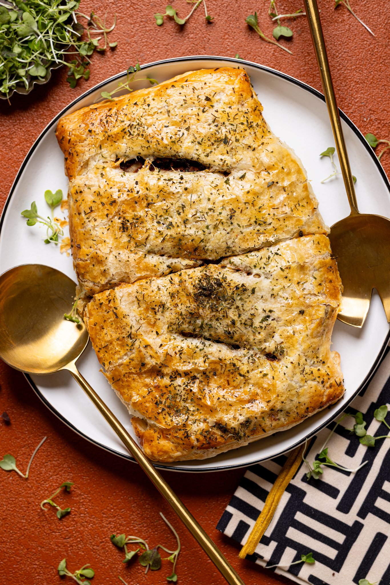 Image of overview of vegan Wellington on a plate with two serving utensils. 