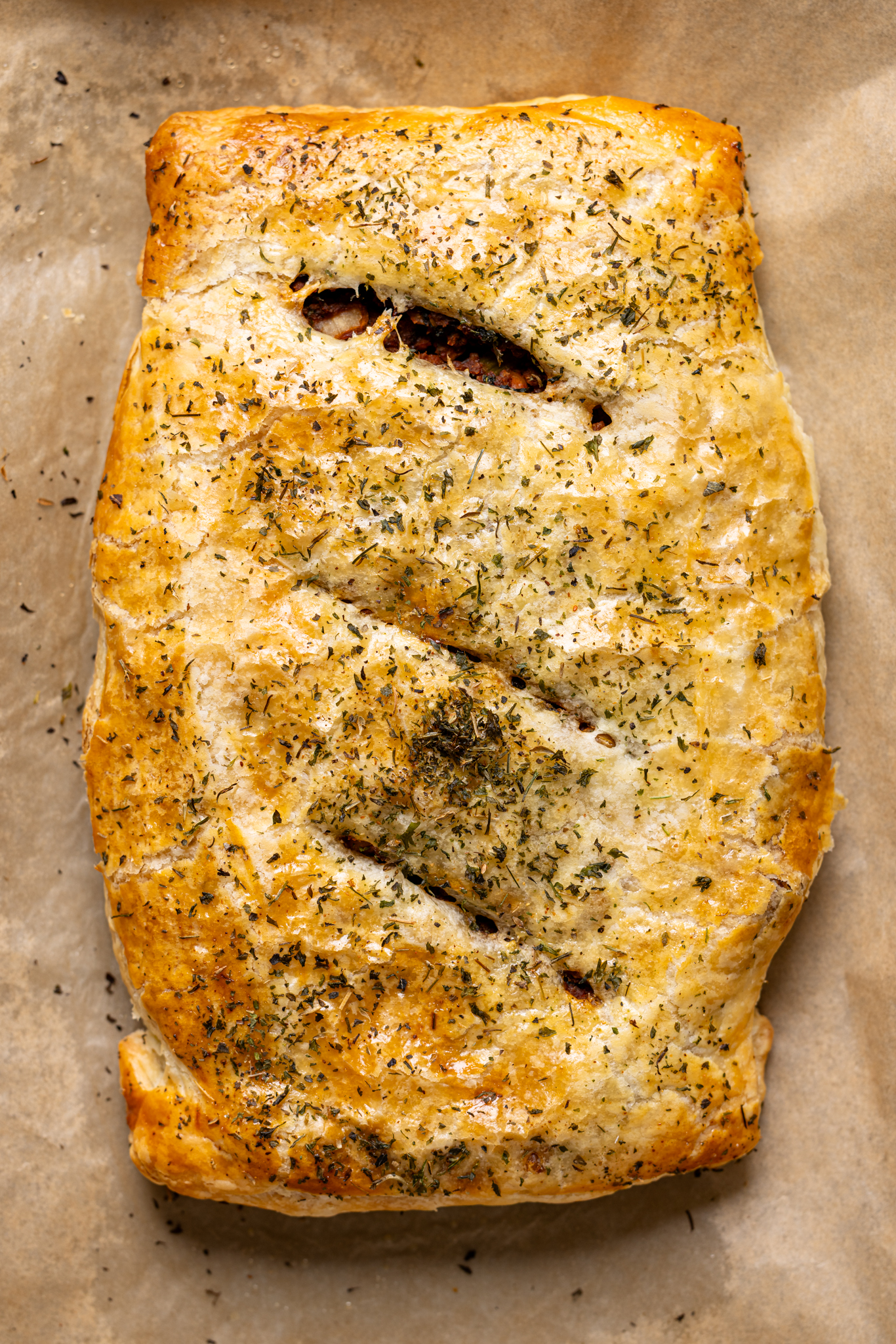 Image of baked beef Wellington on a baking sheet with parchment. 