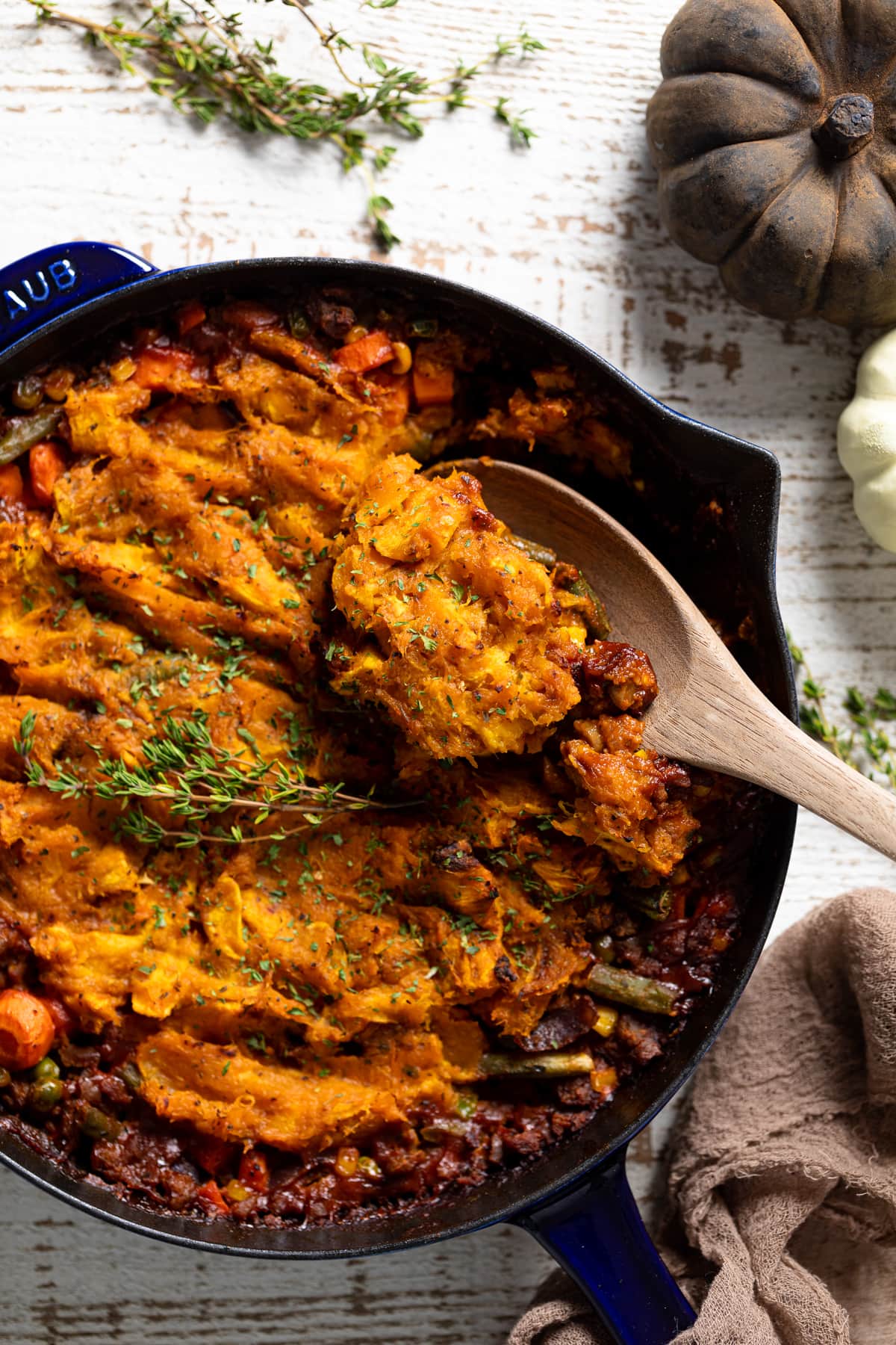 Wooden spoon scooping some Butternut Squash Sweet Potato Shepard’s Pie out of a skillet