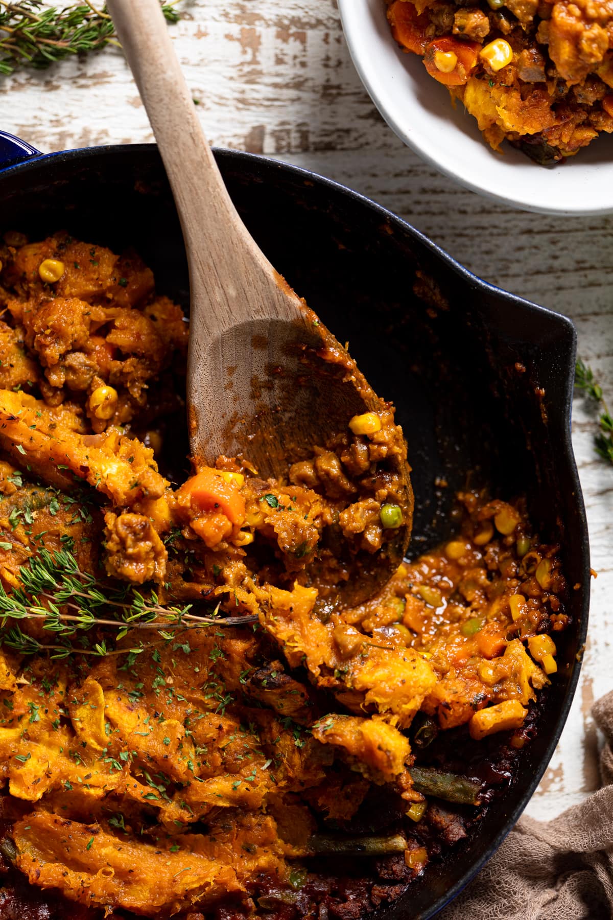 Wooden spoon scooping Butternut Squash Sweet Potato Shepherd’s Pie from a skillet