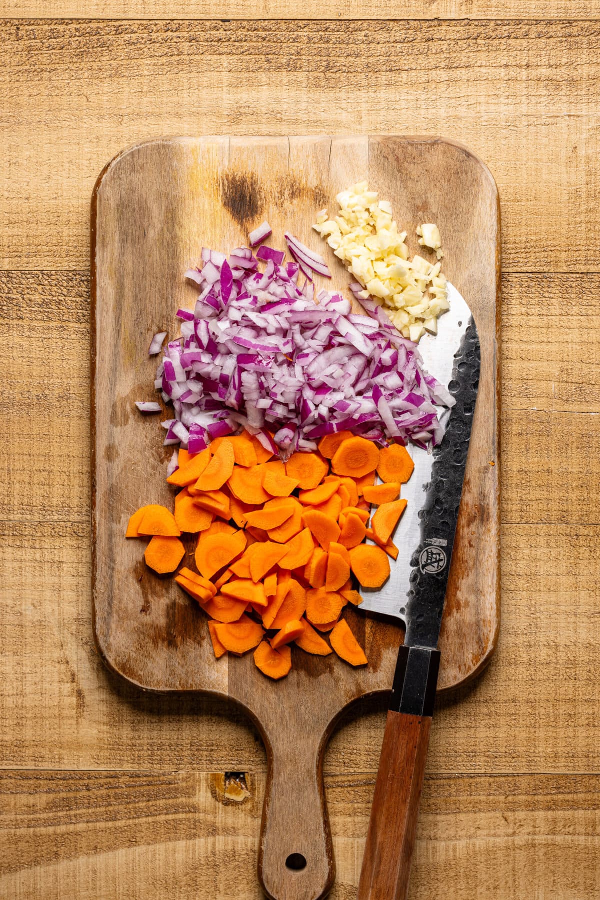 Chopped veggies on a cutting board with a knife. 