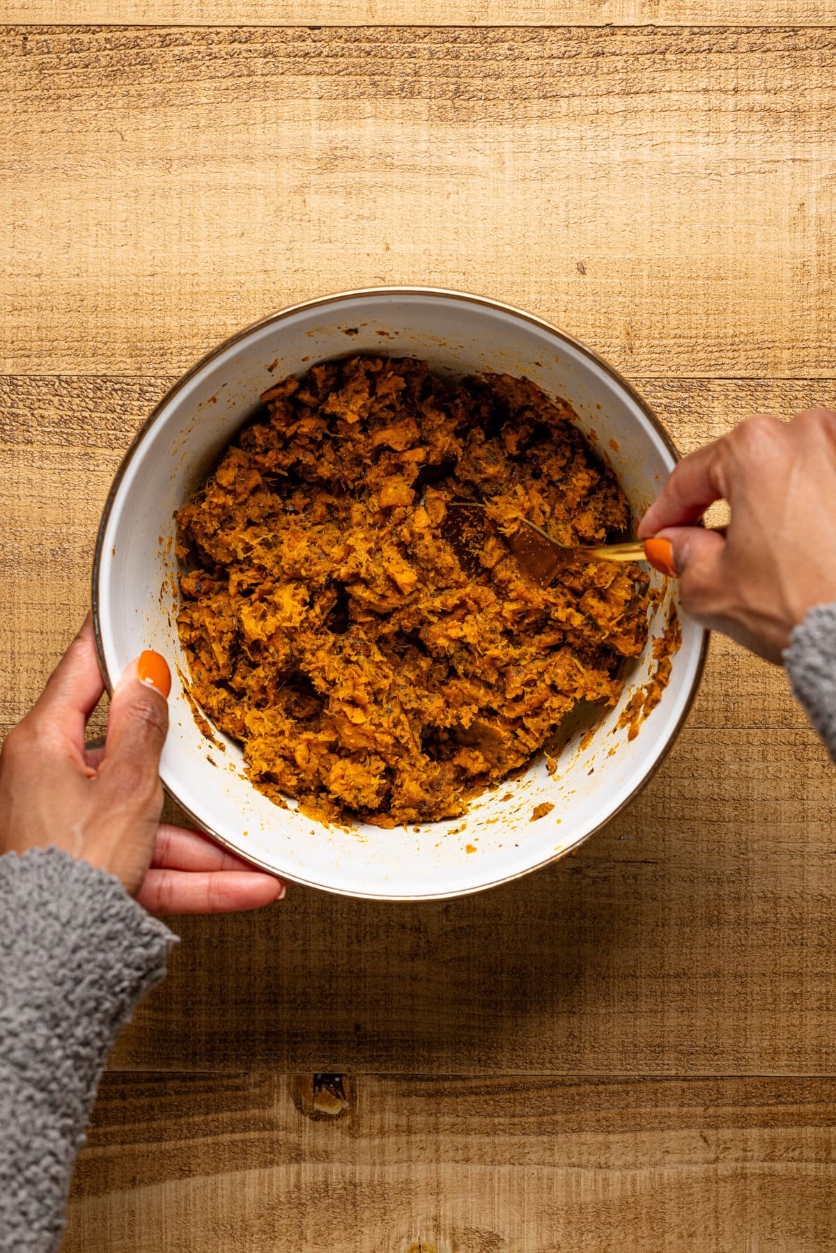 Mashed sweet potato + butternut squash in a bowl being stirred together.