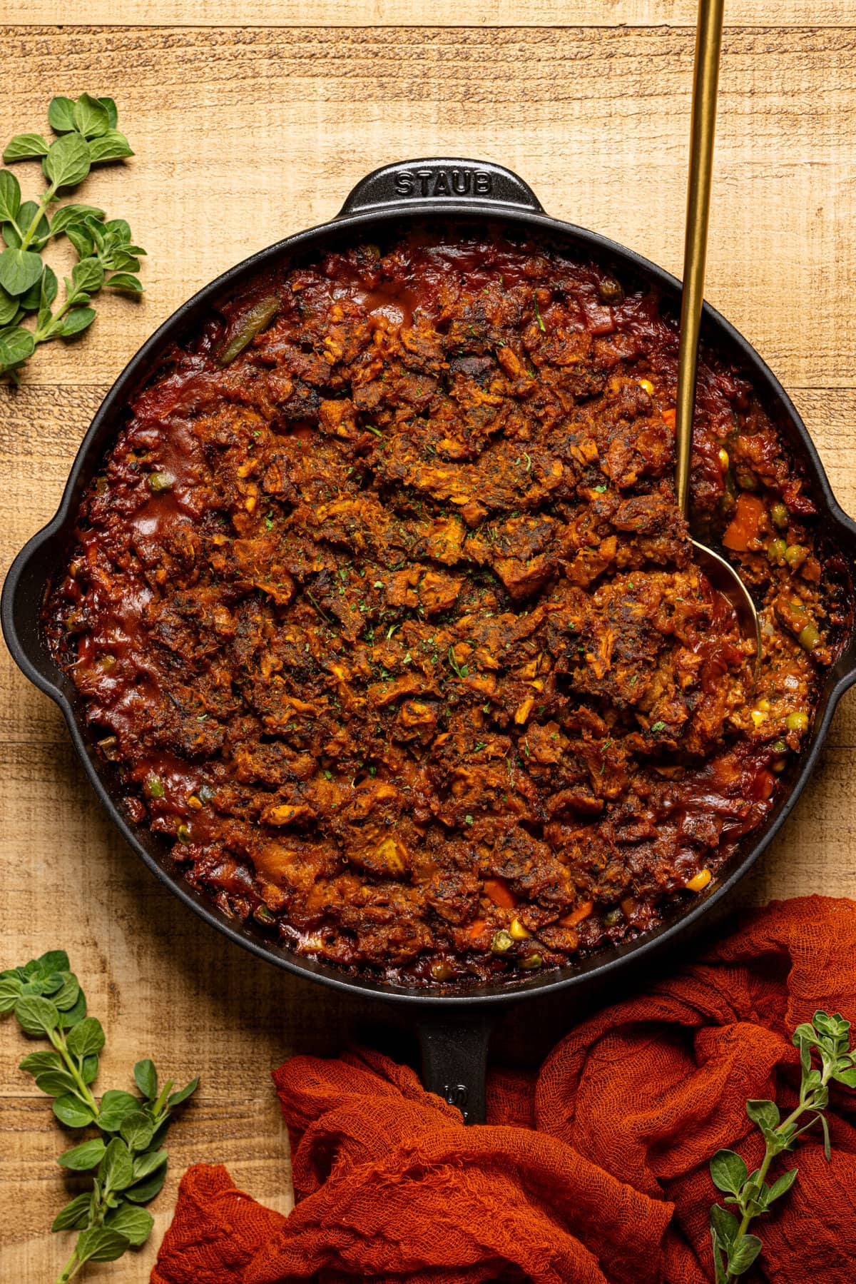 Baked shepherd's pie in a black skillet with a gold spoon.