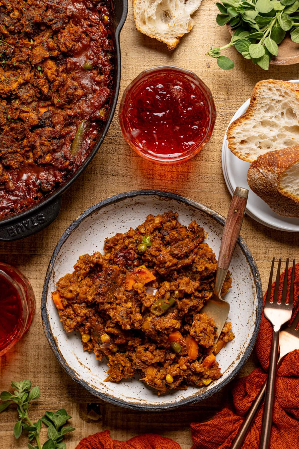 Shepherd's pie in a plate with a fork, side of drinks, and bread.