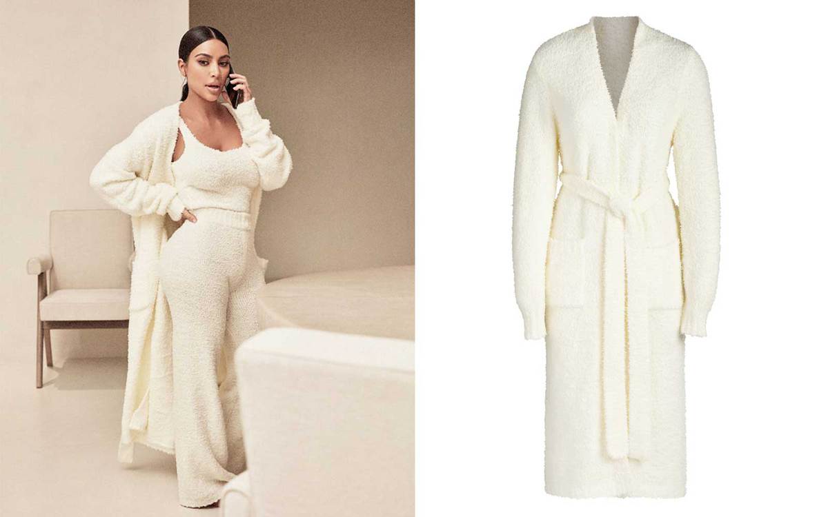 Kim Kardashian talking on the phone while wearing light-colored Skims loungewear