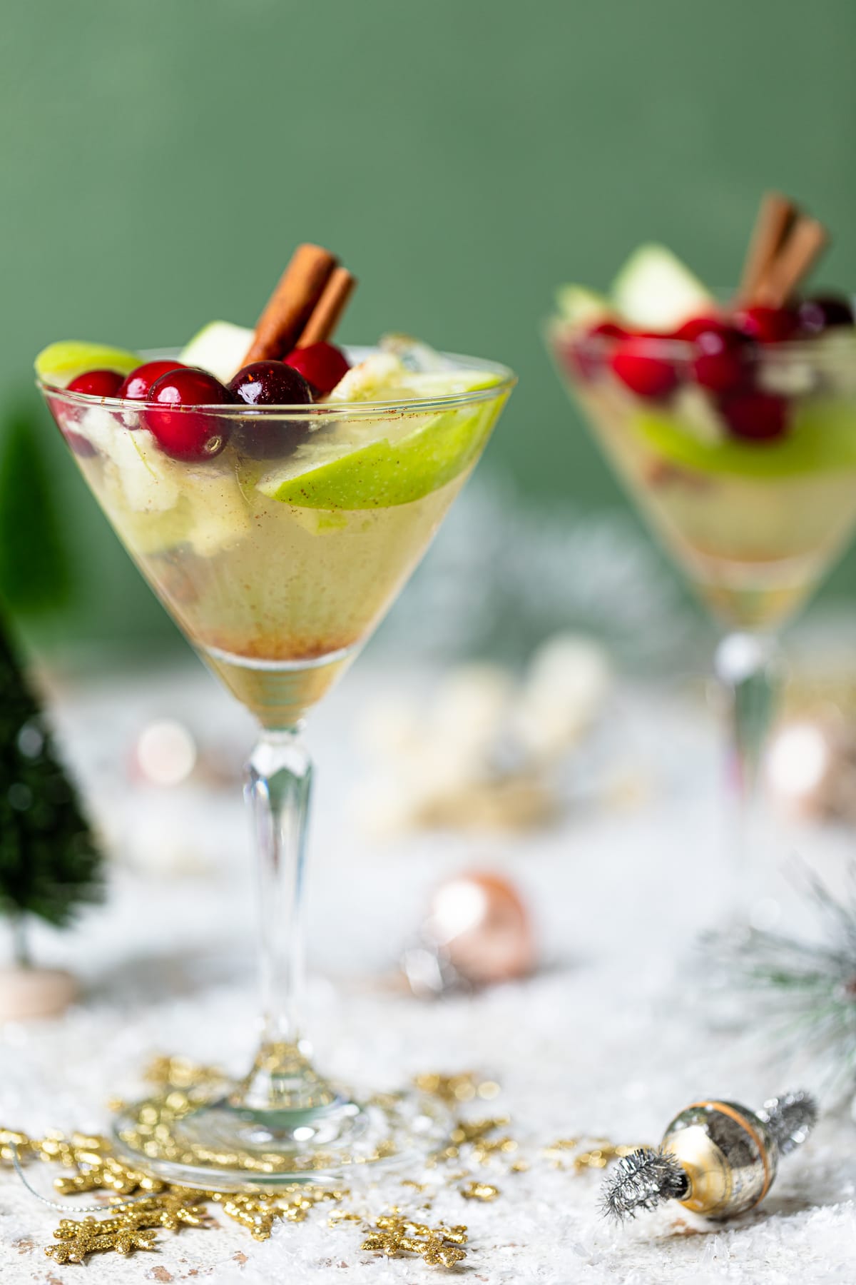 Two Apple White Grape Mocktails in martini glasses on a table set with Christmas decorations