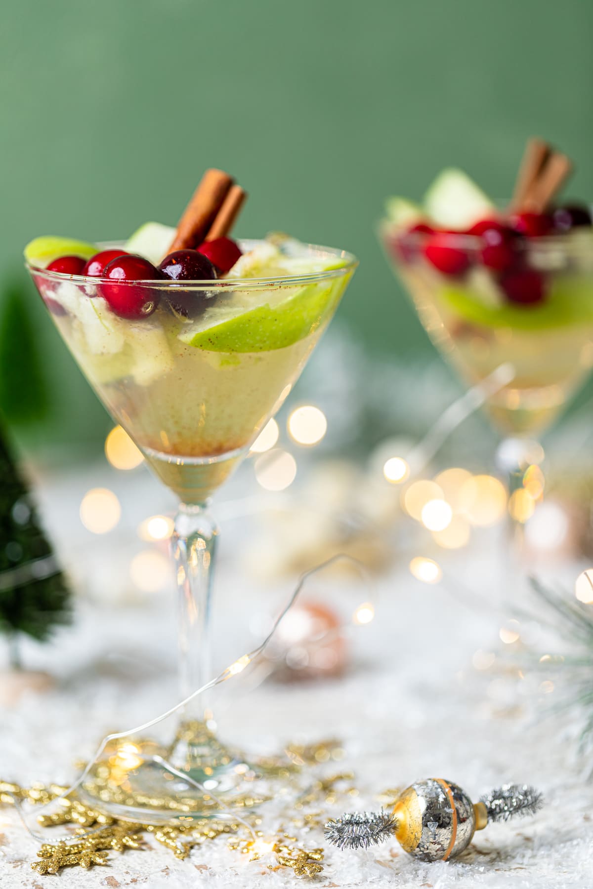 Two Apple White Grape Mocktails set on a table with Christmas decorations