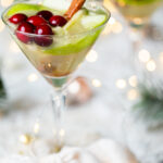 Apple White Grape Mocktail in a martini glass on a table set with Christmas decorations