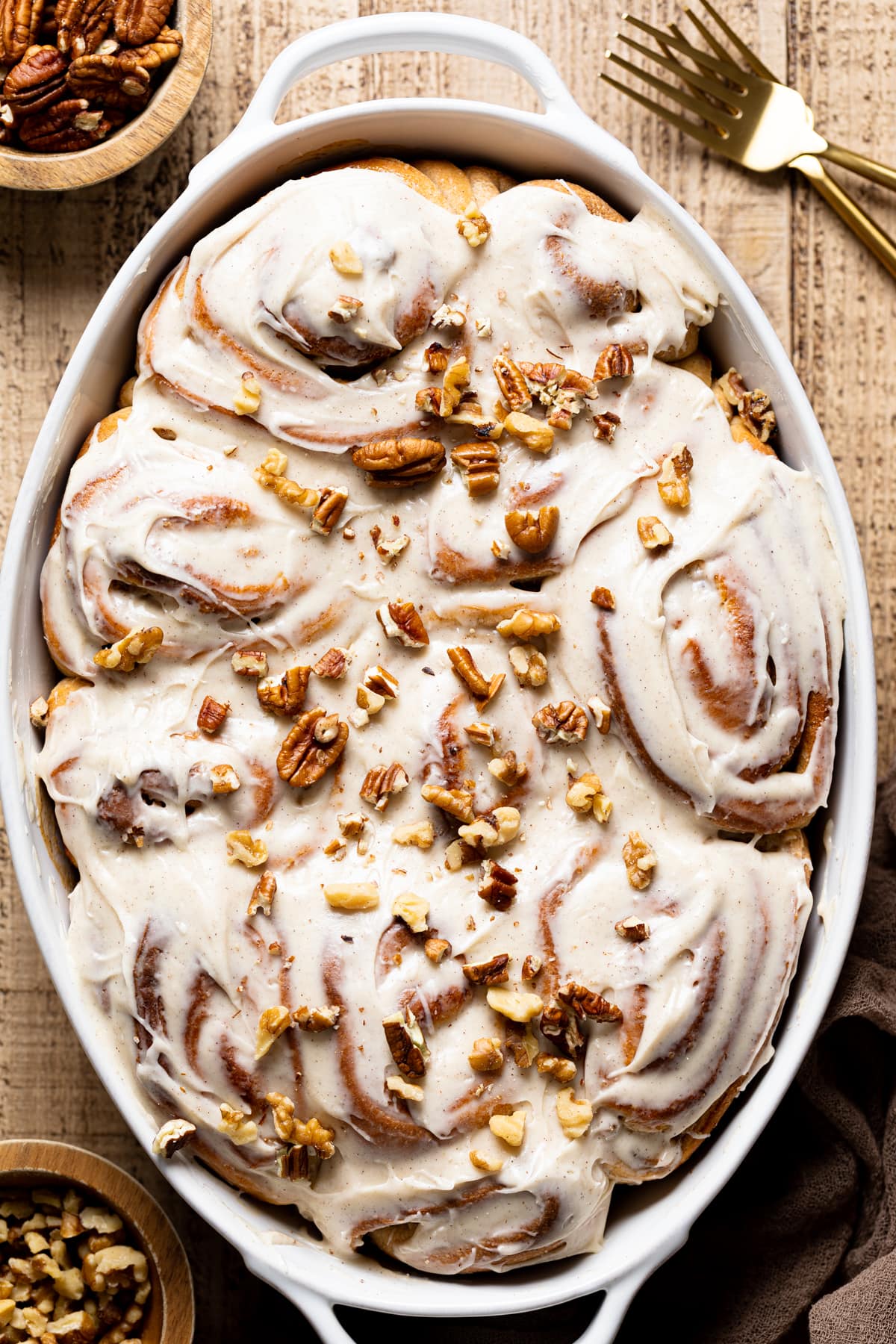 Banana Bread Cinnamon Rolls with Maple Cream Cheese Frosting topped with nuts